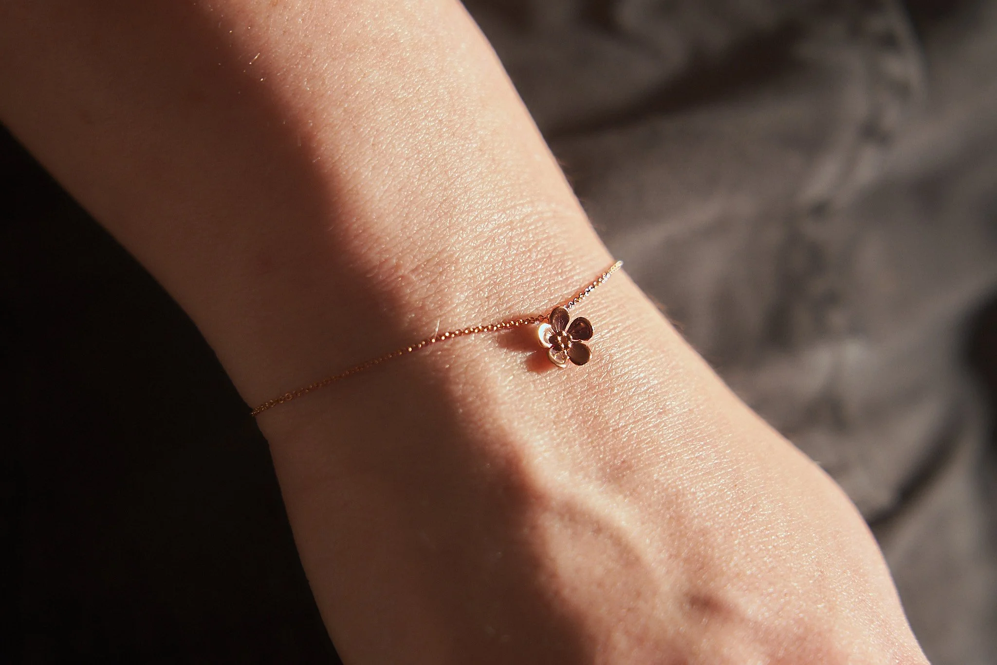 Rose gold forget-me-not bracelet worn on the wrist, showing the delicate scale of the design.