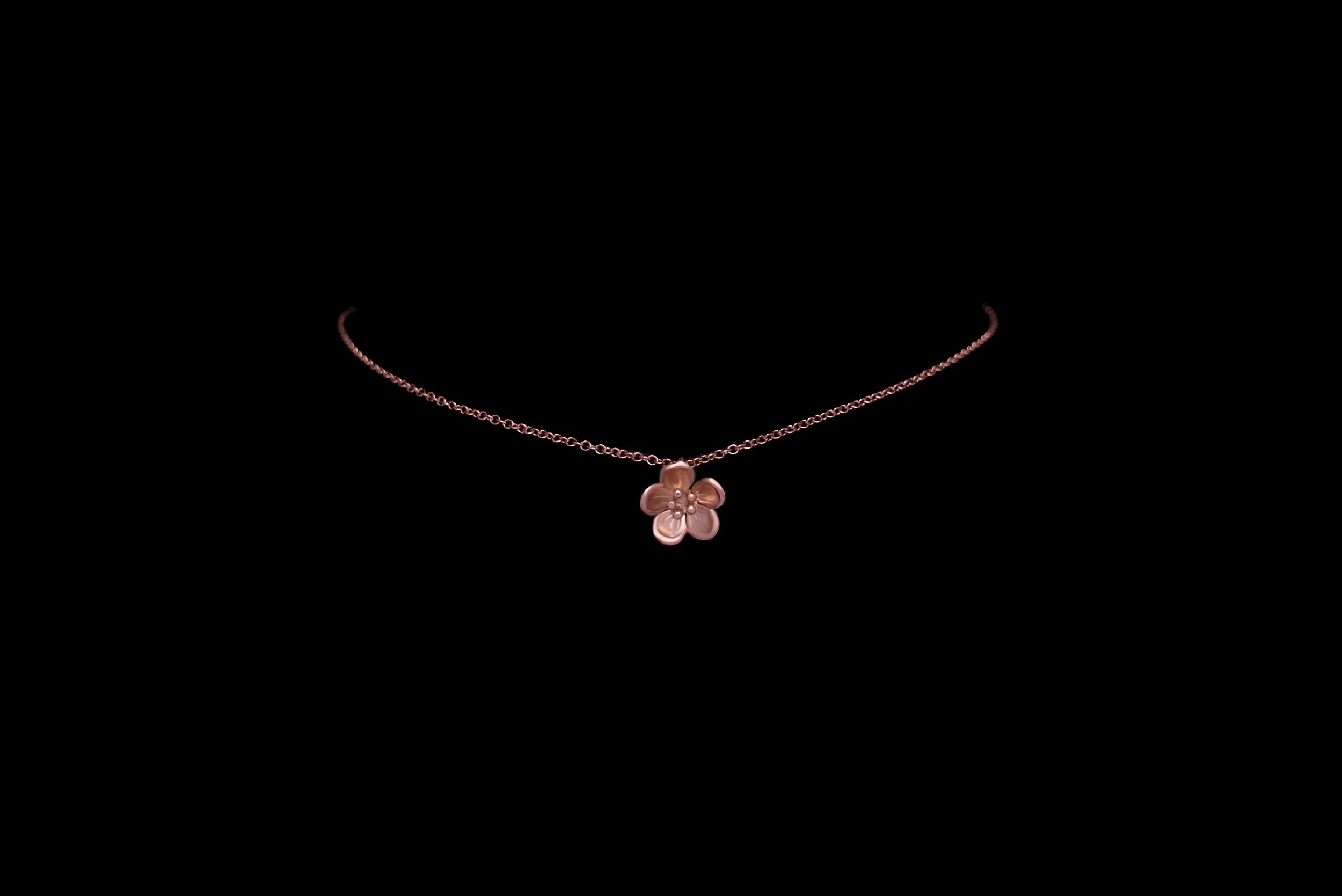 Rose gold forget-me-not bracelet on a fine trace chain photographed against a black background.