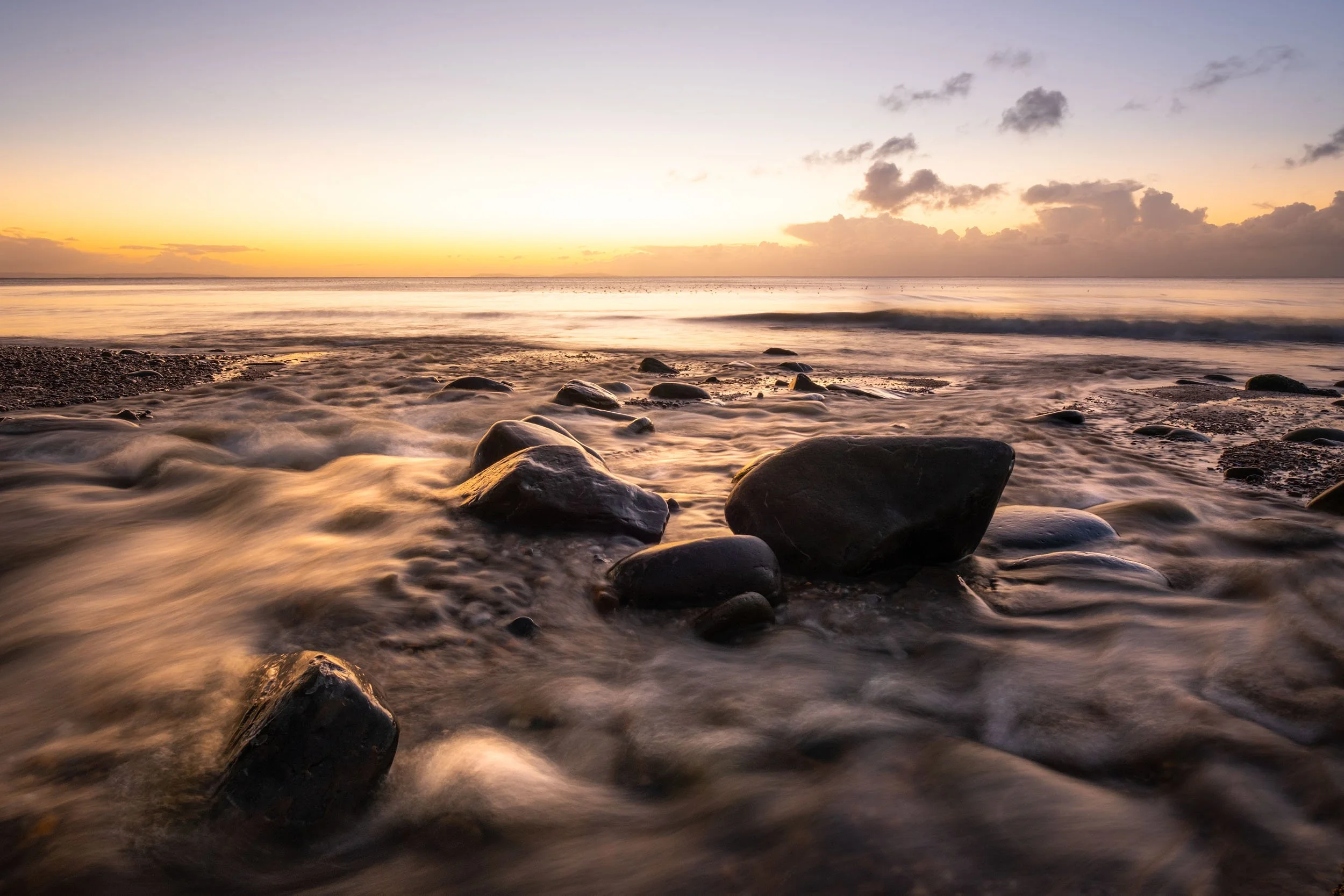 a landscape photo of a river flowing into the sea at sunrise at wiseman's bridge in Pembrokeshire