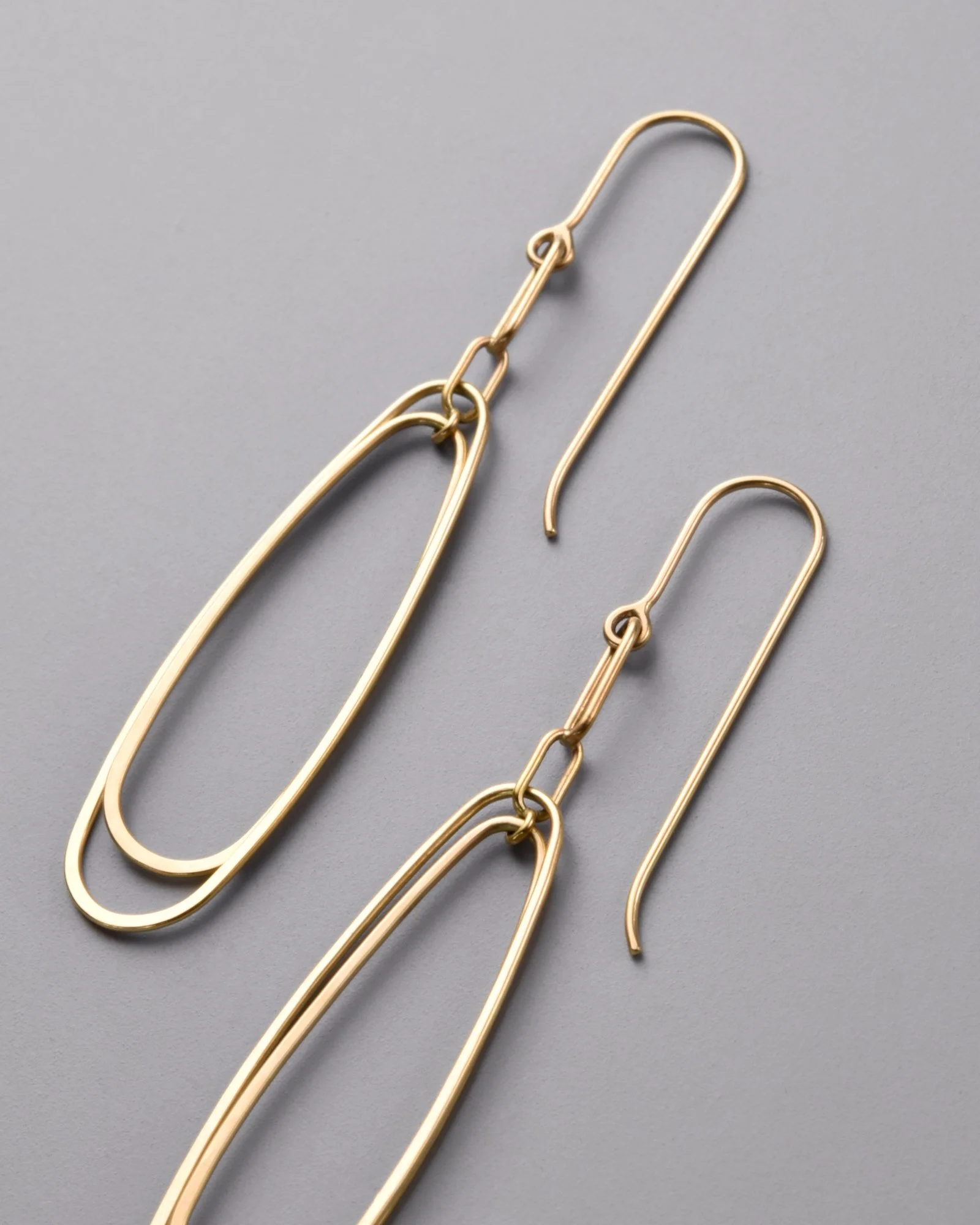 Colette Earrings — close-up detail of the hand-forged 14k yellow gold drop earrings on a grey background