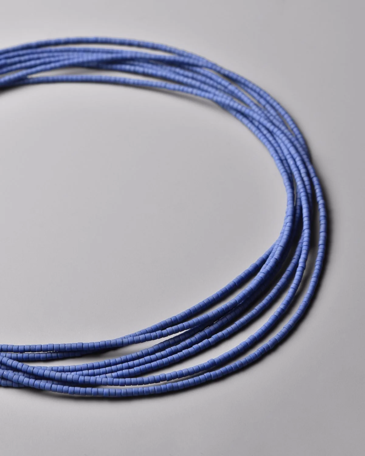 Cobalt Sweep Necklace — close-up flat-lay detail of the vivid cobalt blue Japanese glass bead strands on a grey background