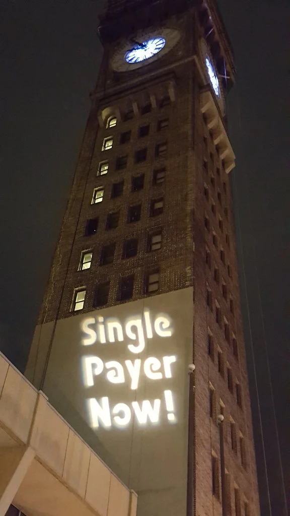 Maryland Solidarity Brigade Guerrilla Light Projections calling for Single Payer Now and Medicare For All on the clocktower ( Backbone Campaign )