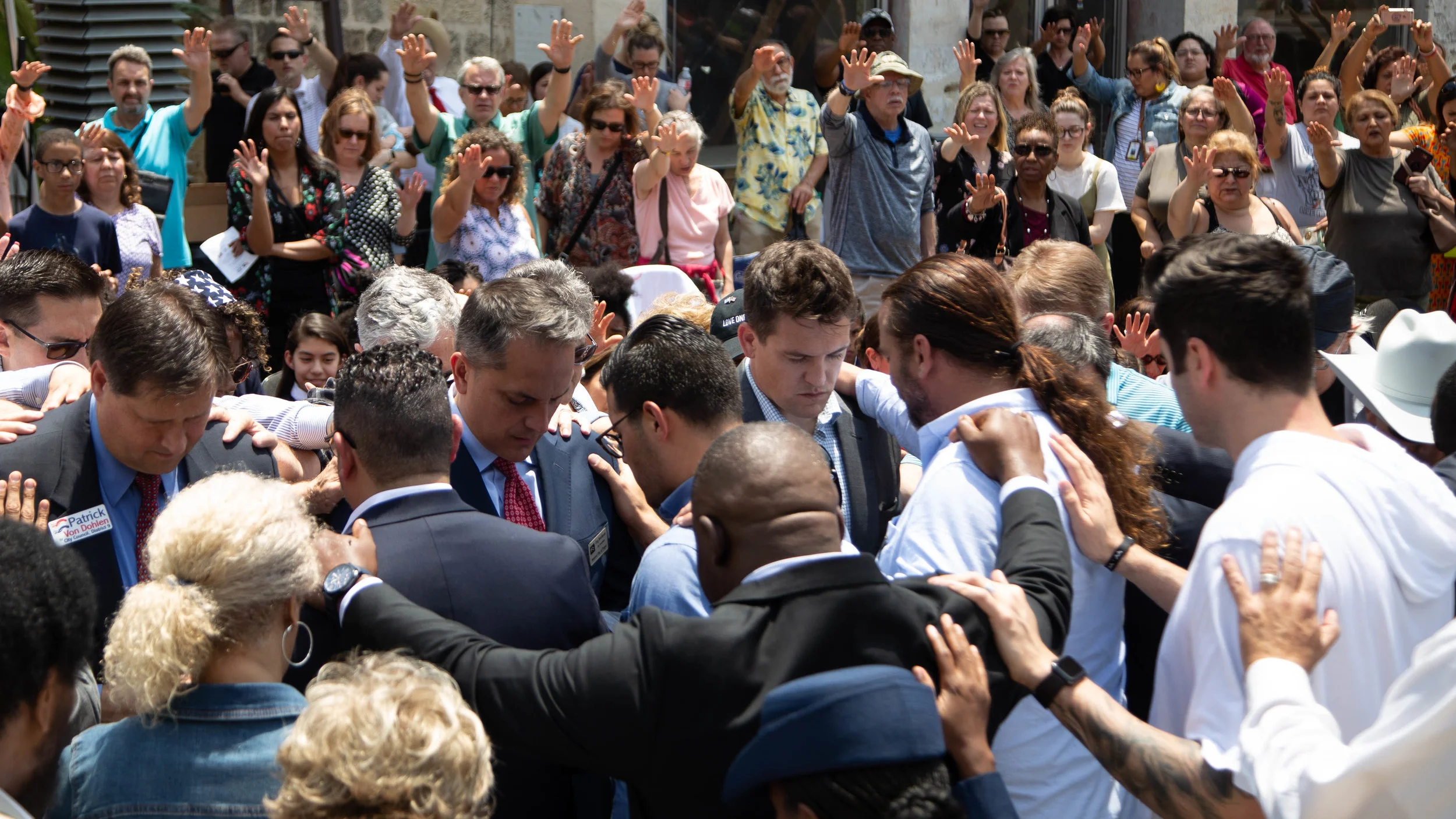Patrick Von Dohlen, Greg Brockhouse, and Trevor Whitney (Left to Right) pray in Main Plaza while attendees place their hands upon them. (Photo by GA Media Productions .)