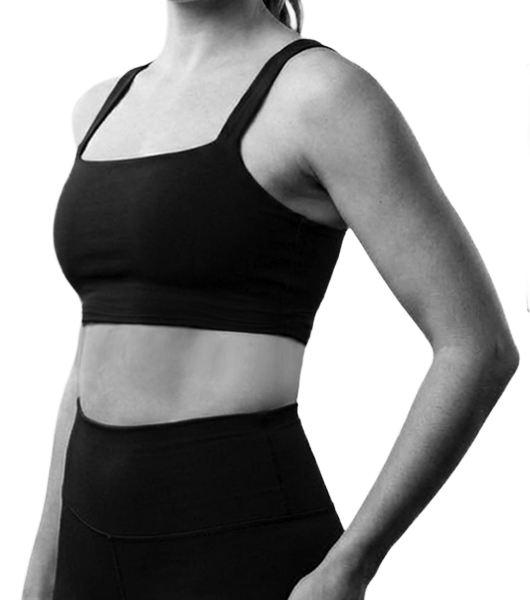 A woman wearing a black sports bra and high-waisted athletic leggings, showing her torso and arm in black and white.