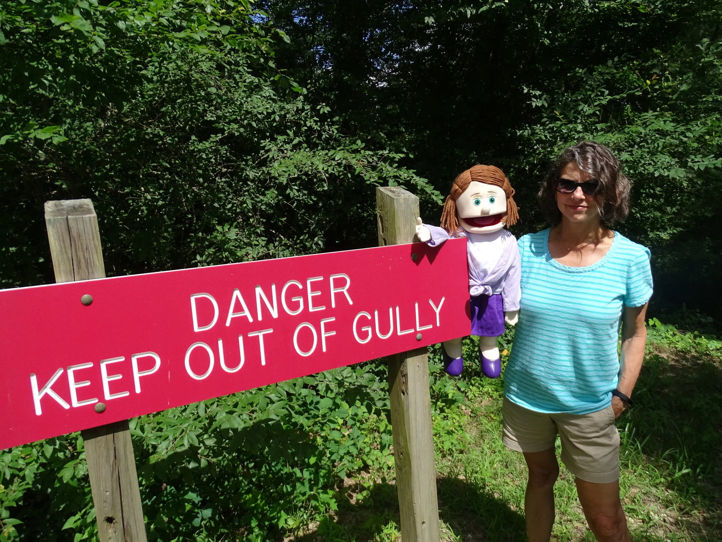 Arla points at a sign that makes it clear the Poverty Point gully is dangerous.