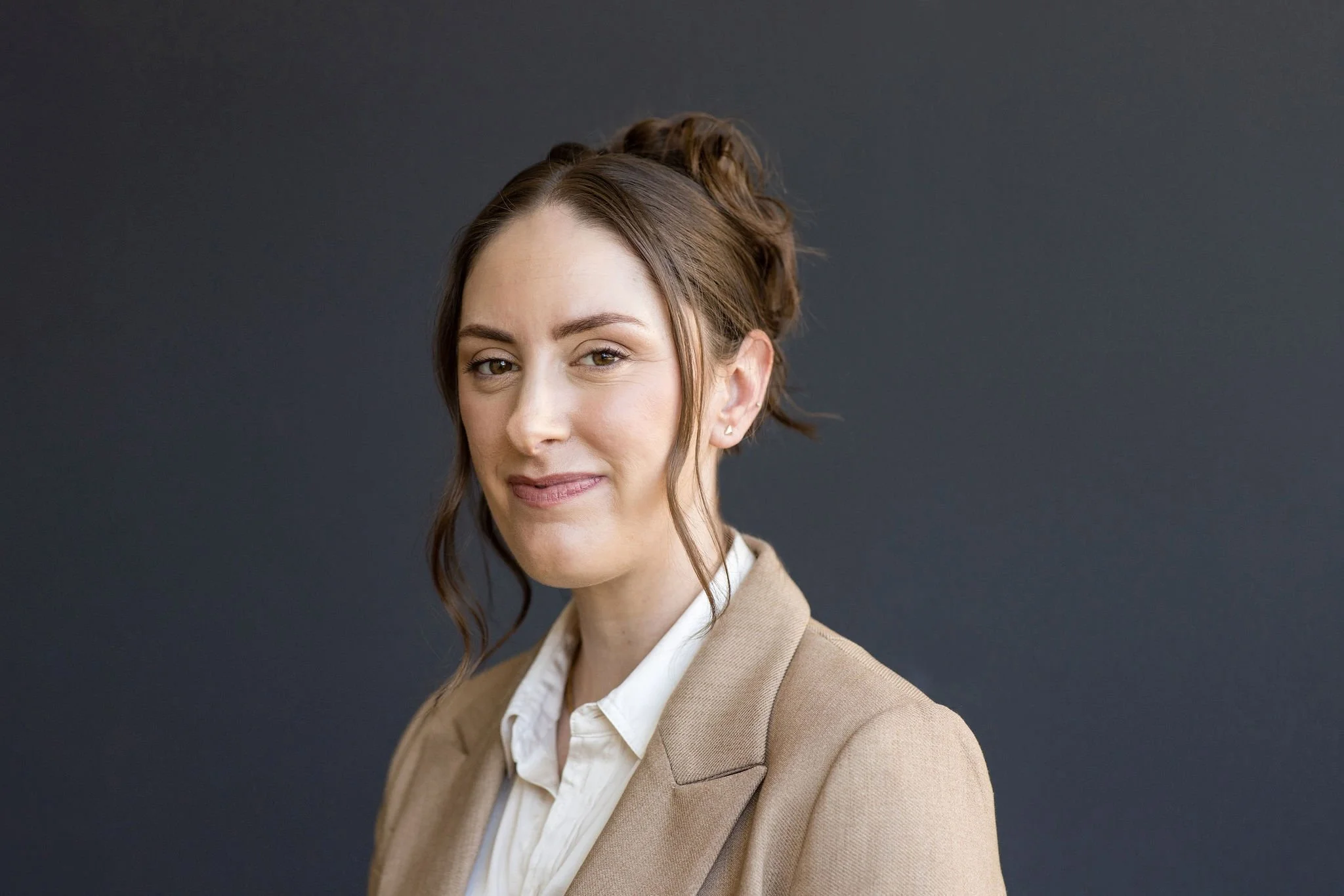 Dietitian nutritionist in a tan suit smiles subtly at the camera