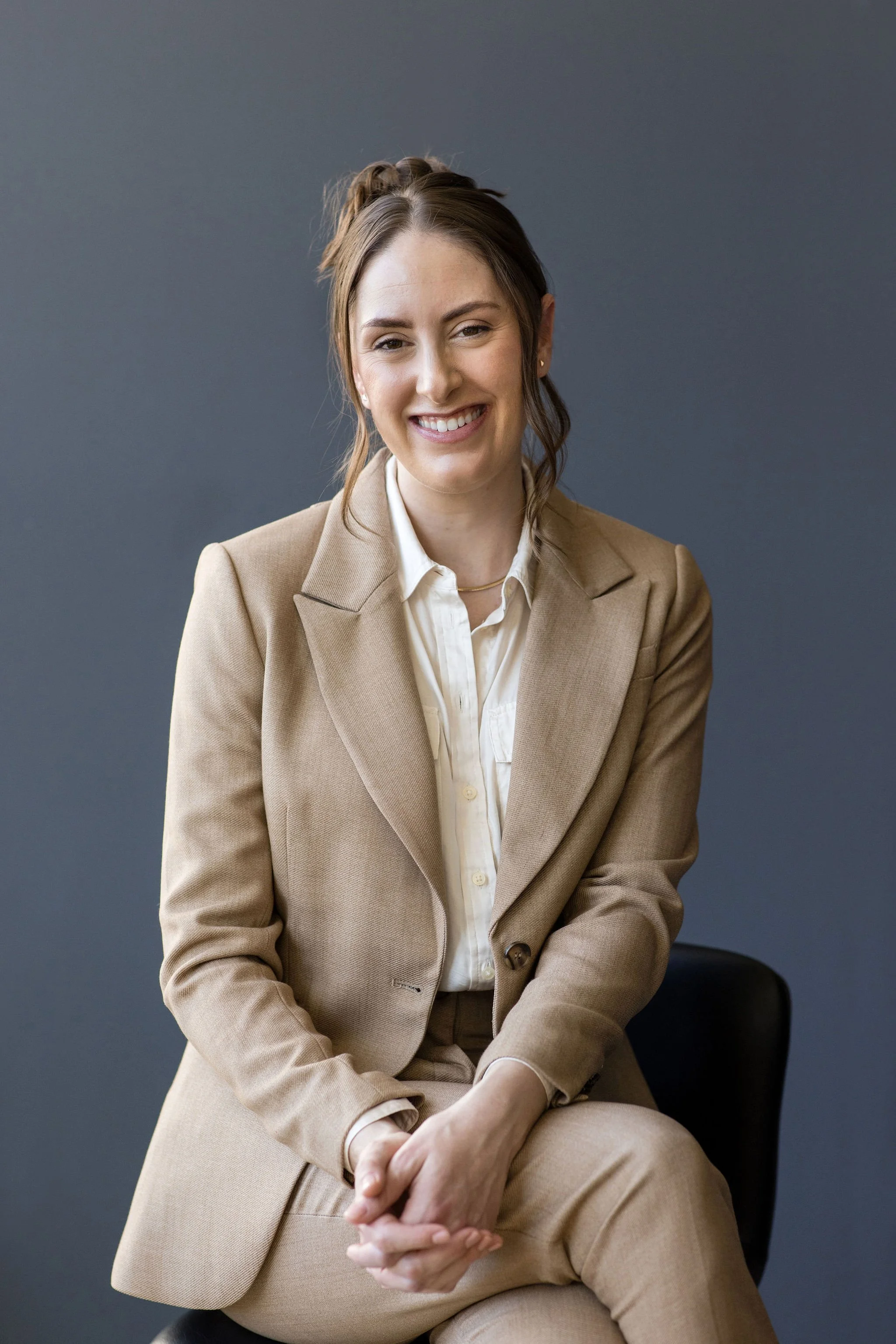Eating disorder dietitian in a tan suit smiling with her hands clasped