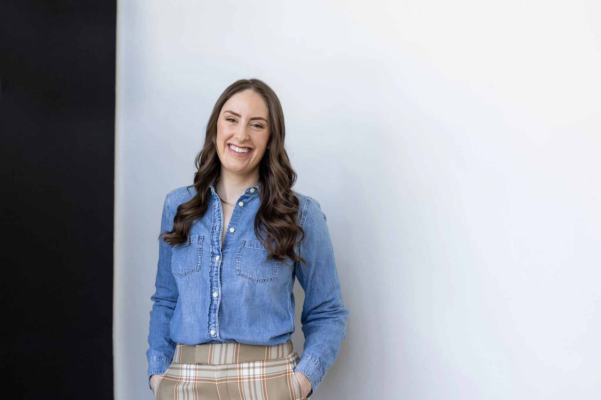 Adolescent FBT dietitian in a denim shirt smiles against a black and white backdrop