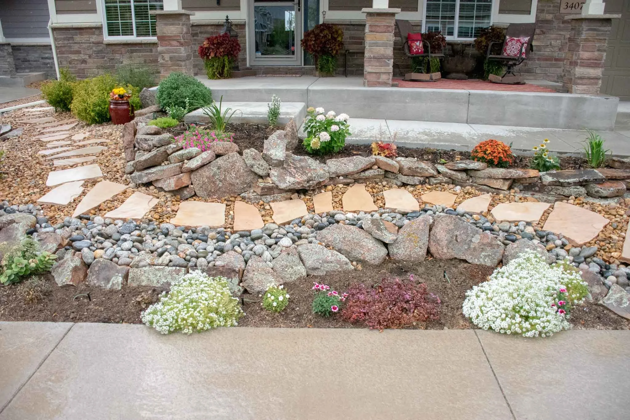 Front yard xeriscape that Tri City designed and completed in Loveland, CO 2019 Cobble stone dry river bed and flagstone pathway.