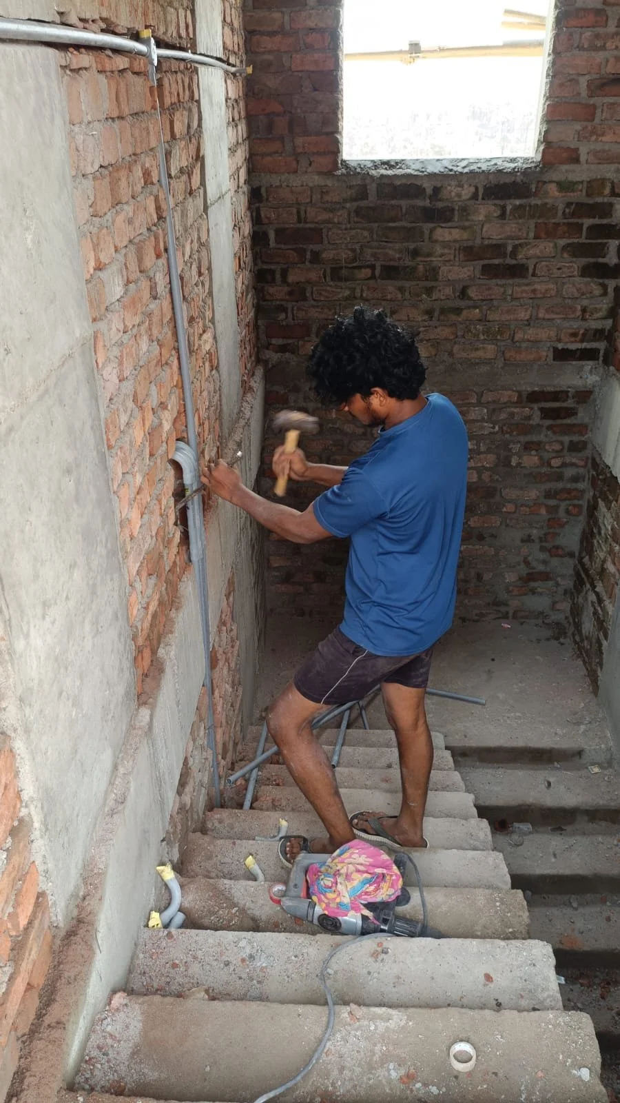 CFC Grad, Ramesh, prepping stairwell brickwork for plaster.