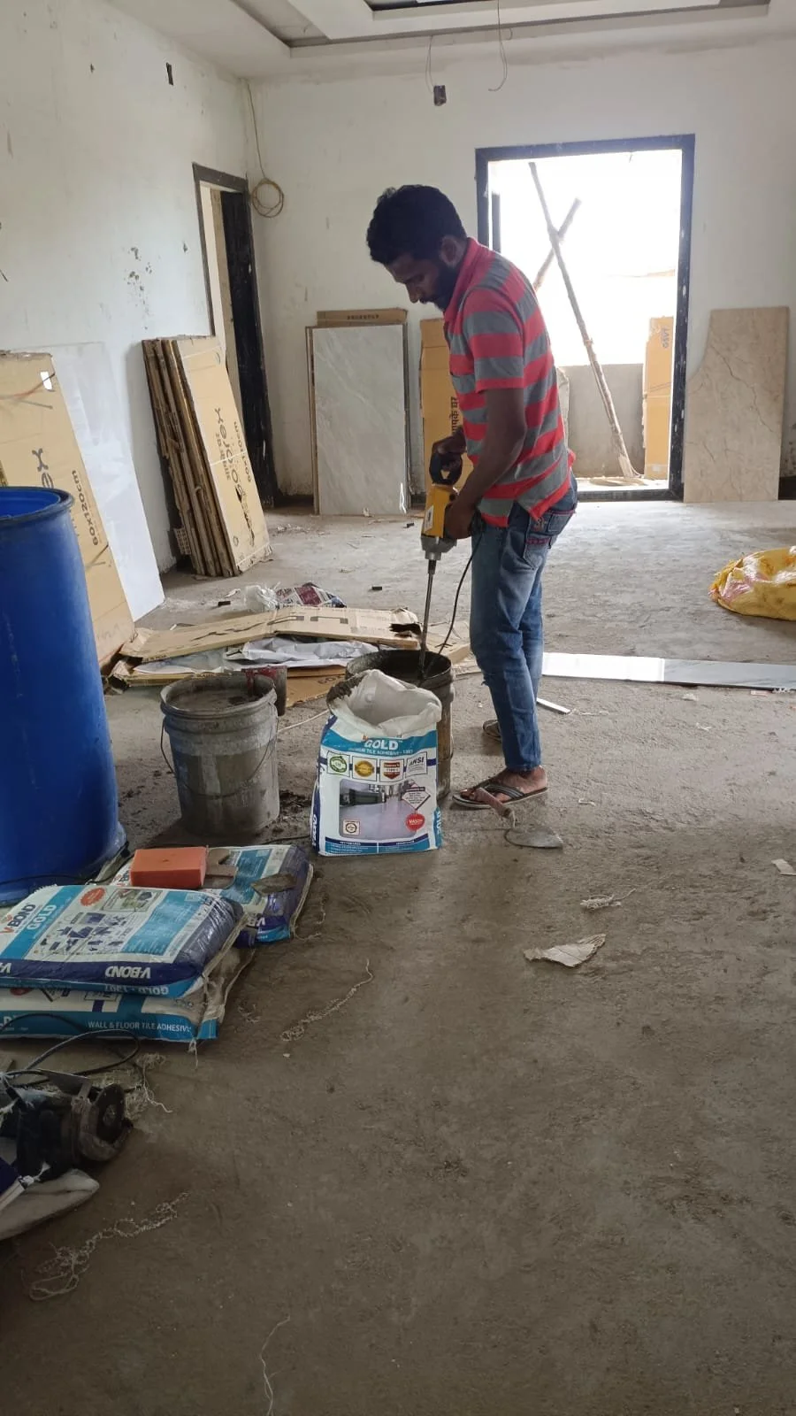 Worker mixing grout for ongoing tiling of floors and bathrooms.