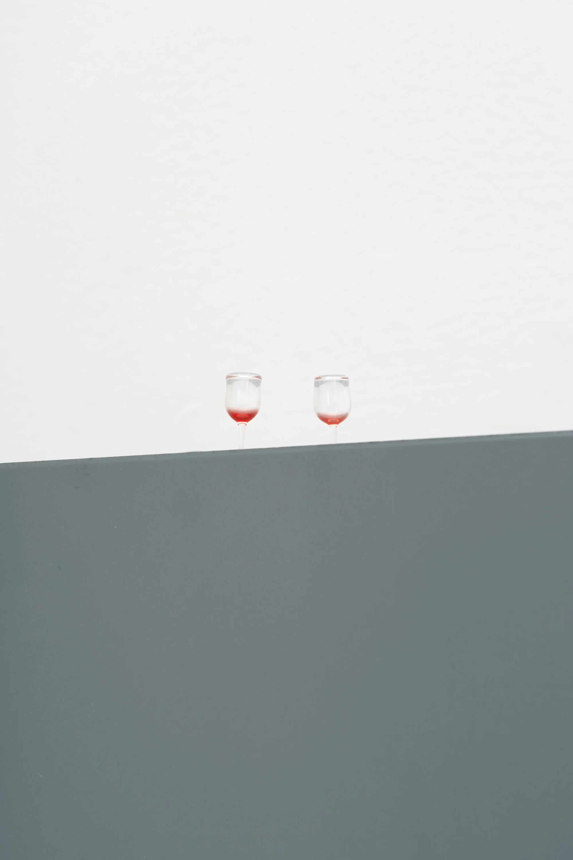 two tiny wine glasses with leftover red wine