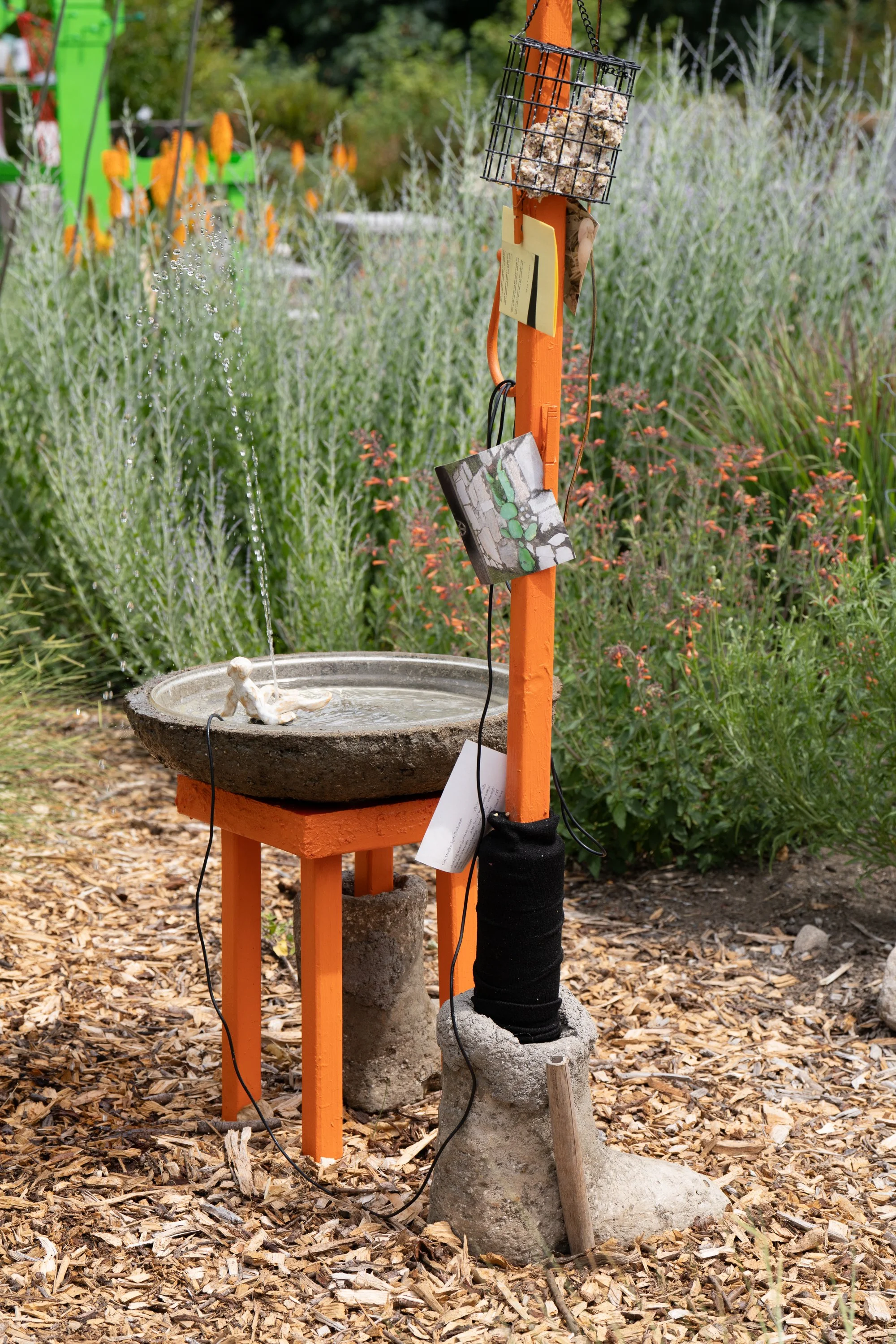 A water fountain featured on a orange sculpture.