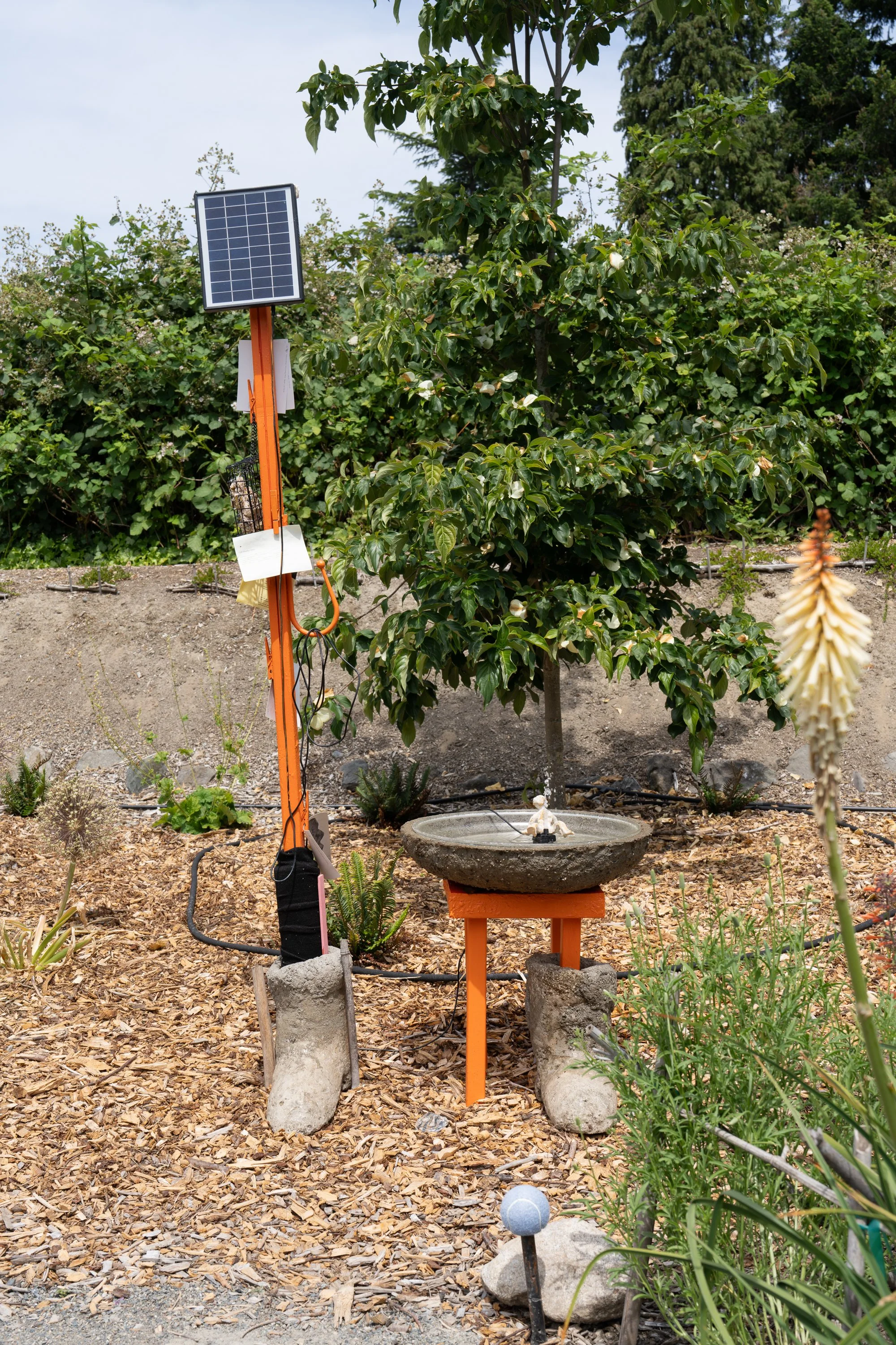 An orange sculpture in a garden.