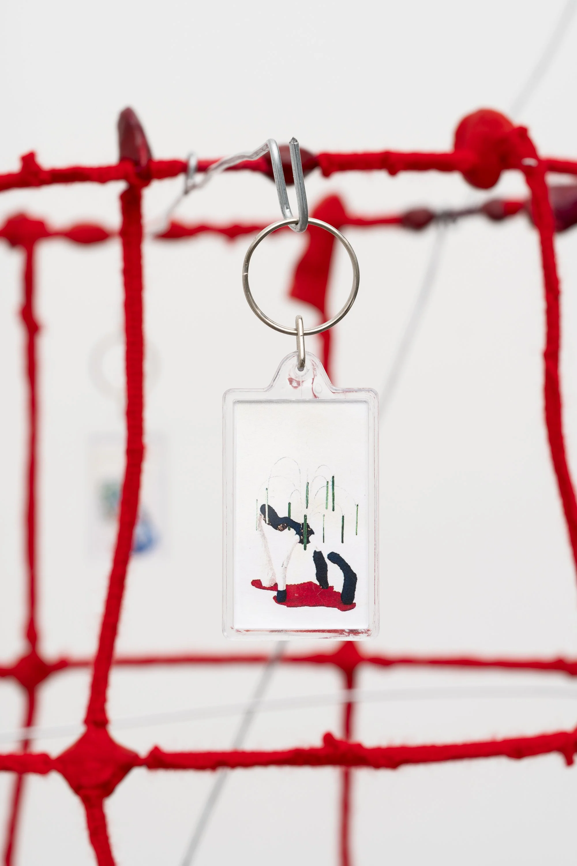a wire tower wrapped in red yarn, with key chains hanging from bent wires