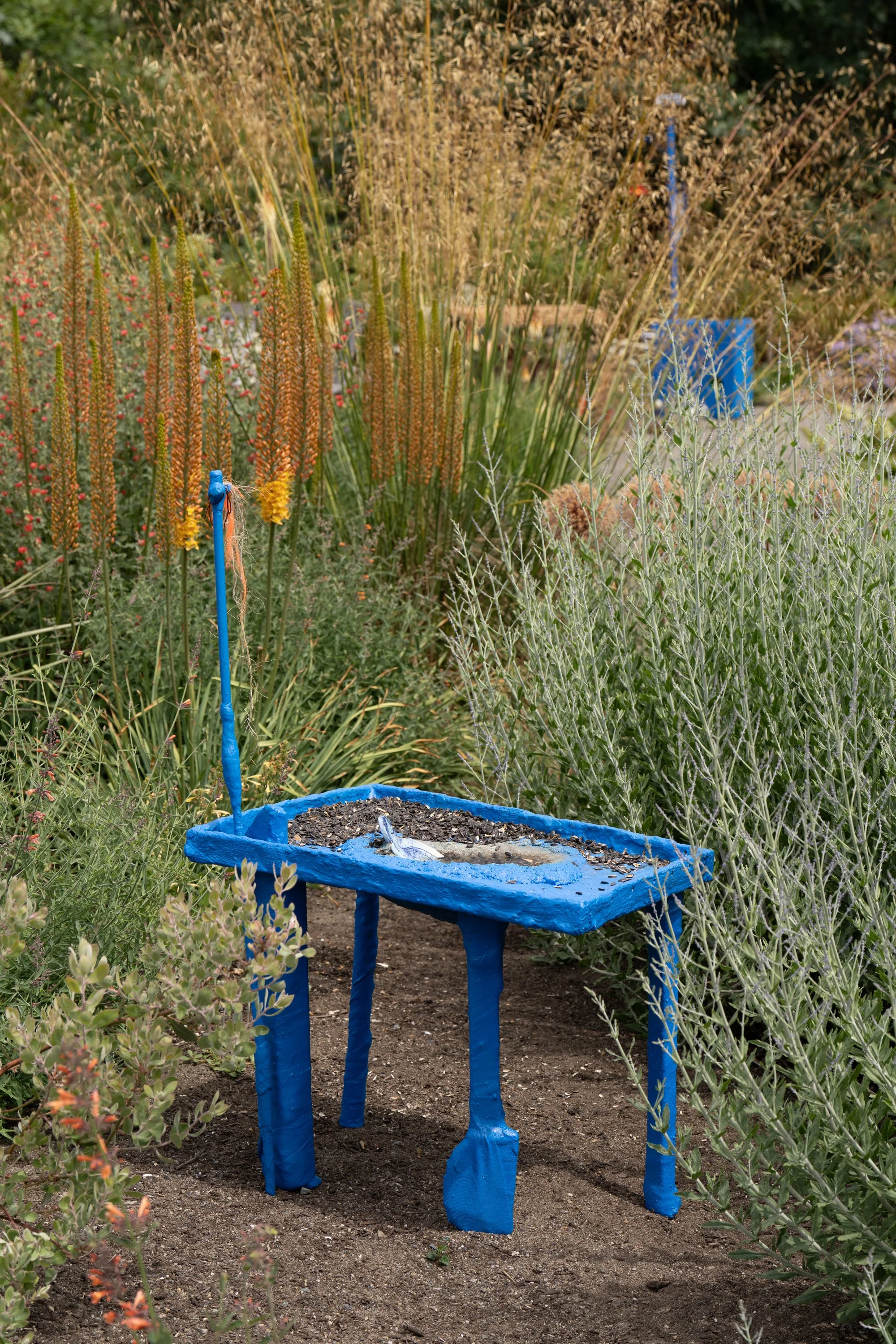 Blue sculpture with sunflower seeds in a garden.