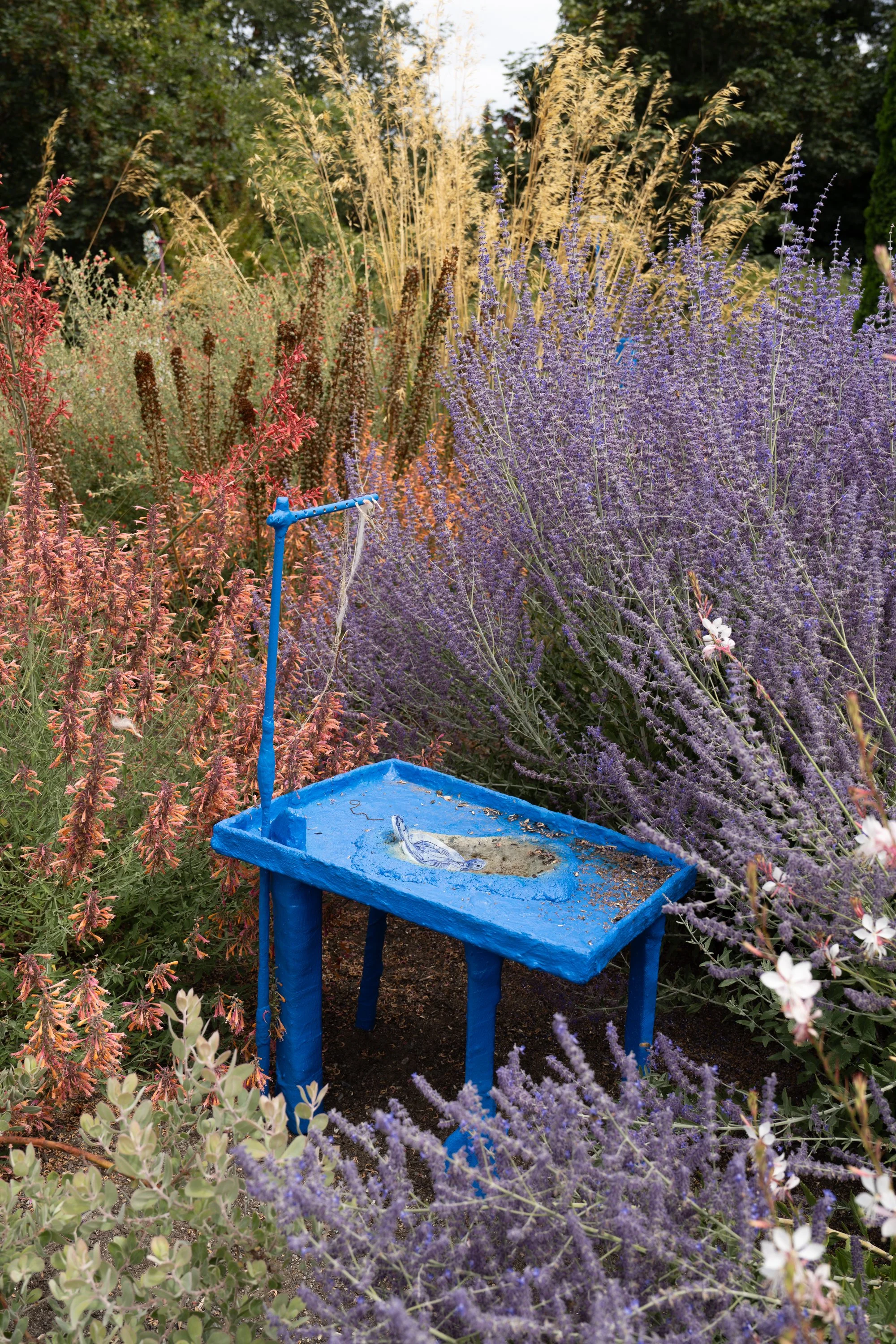 Blue sculpture with ceramic plate in a garden.
