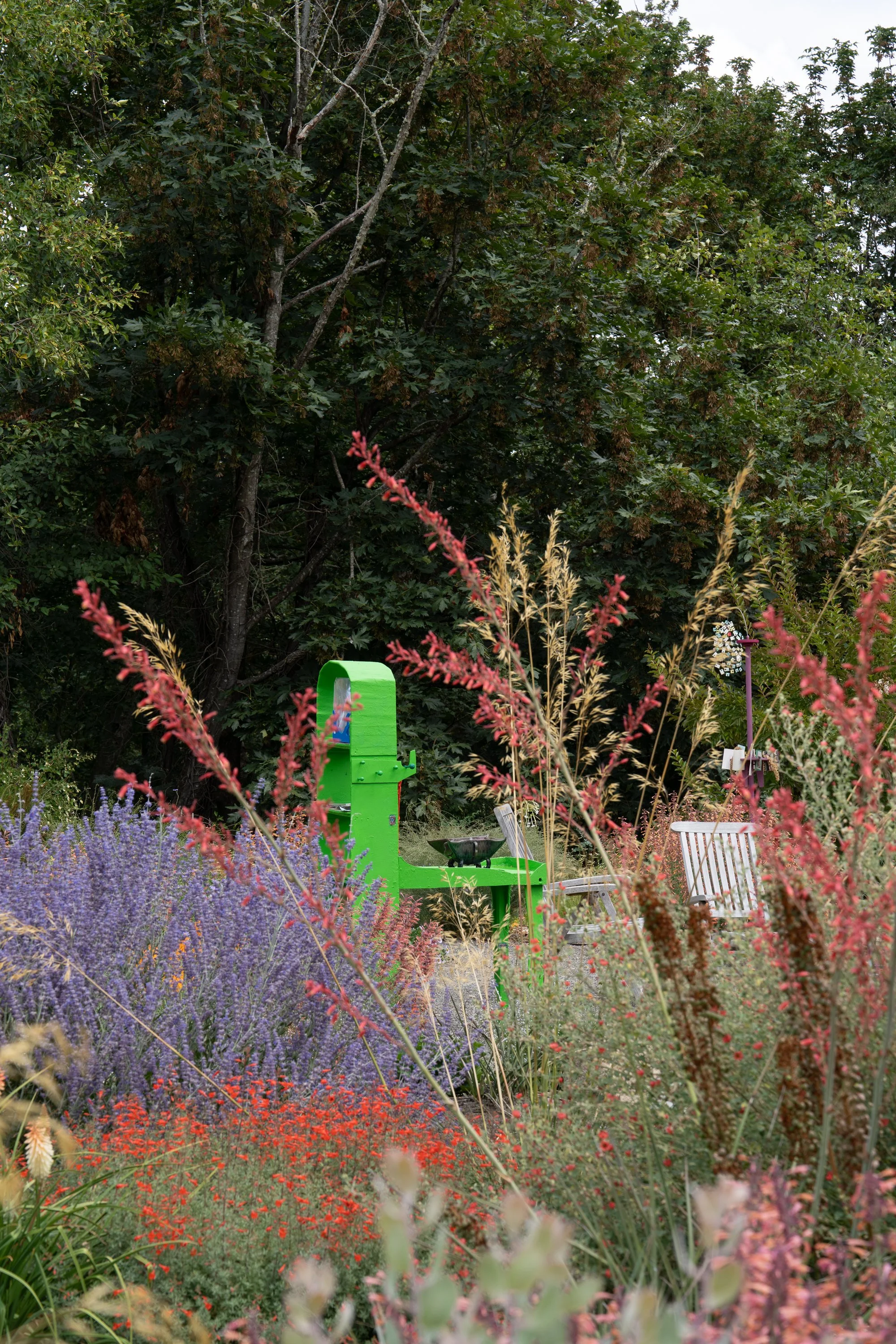 A green sculpture behind colorful blooms.