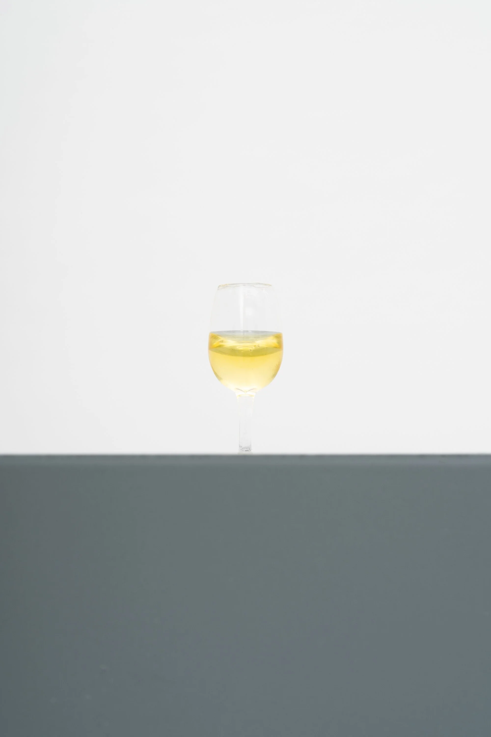 a tiny wine glass half fall with white wine