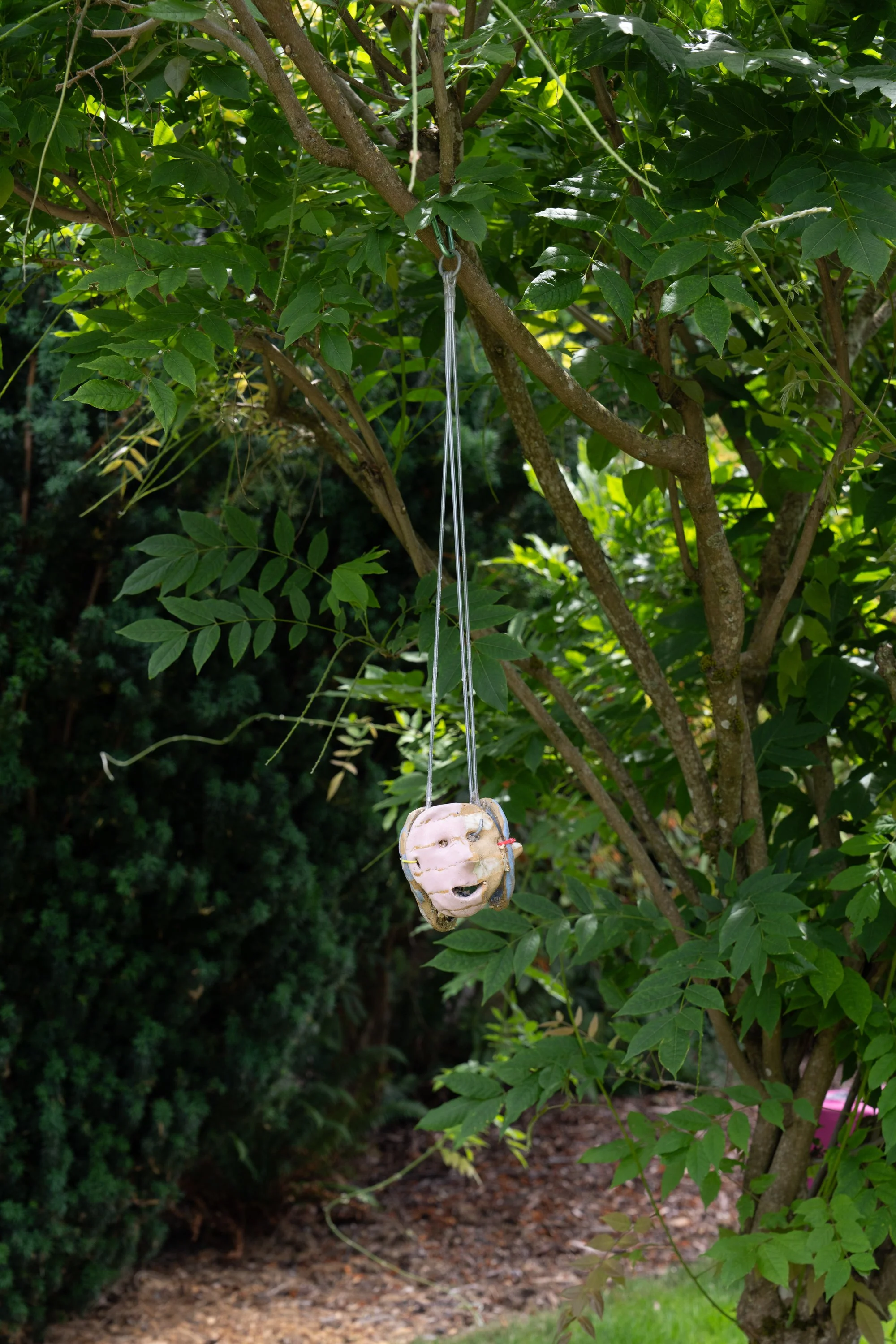 A ceramic sculpture hanging from a tree.