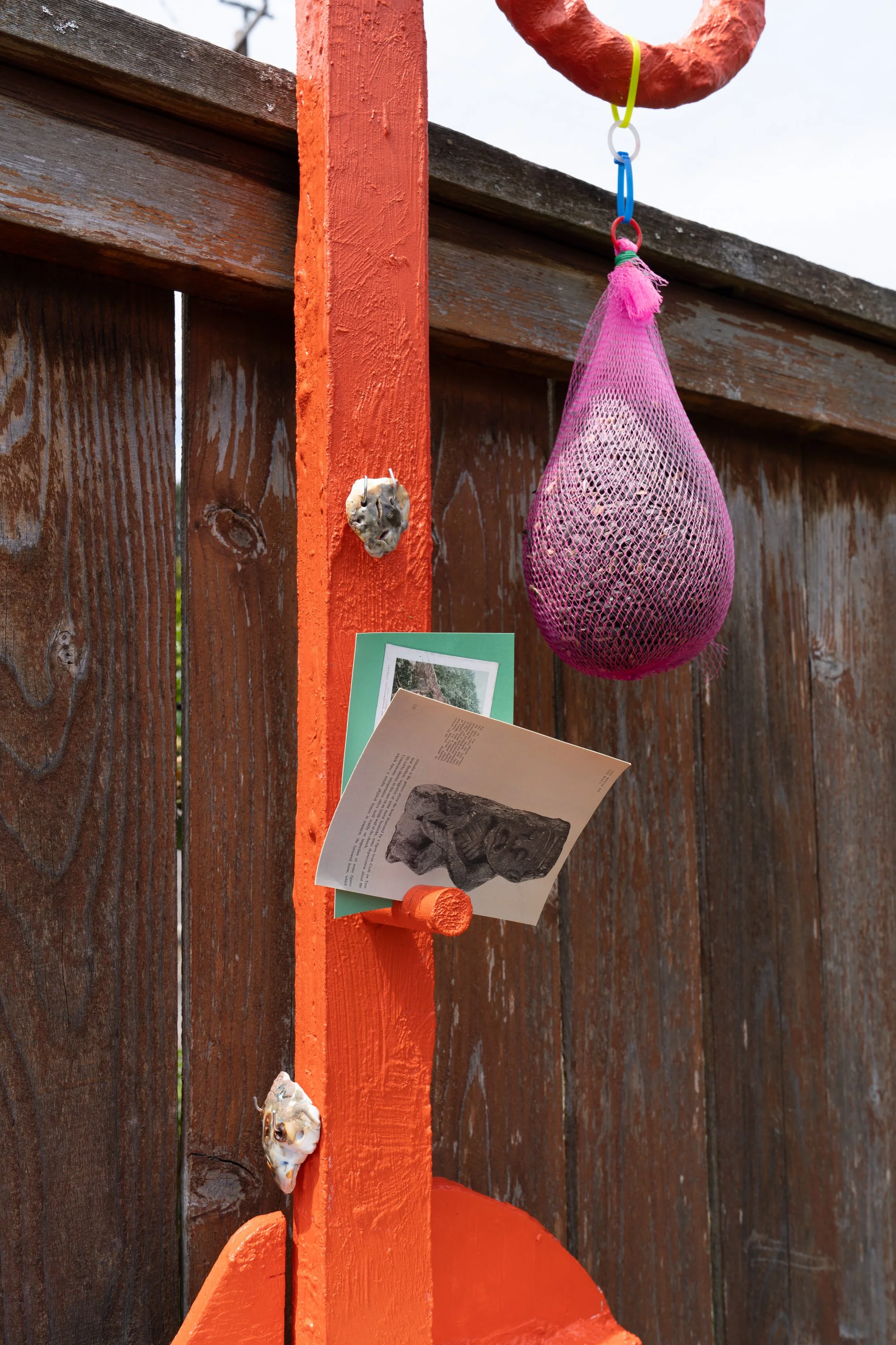 ceramic masks, postcards, and a bag of sunflower seeds on an orange sculpture.