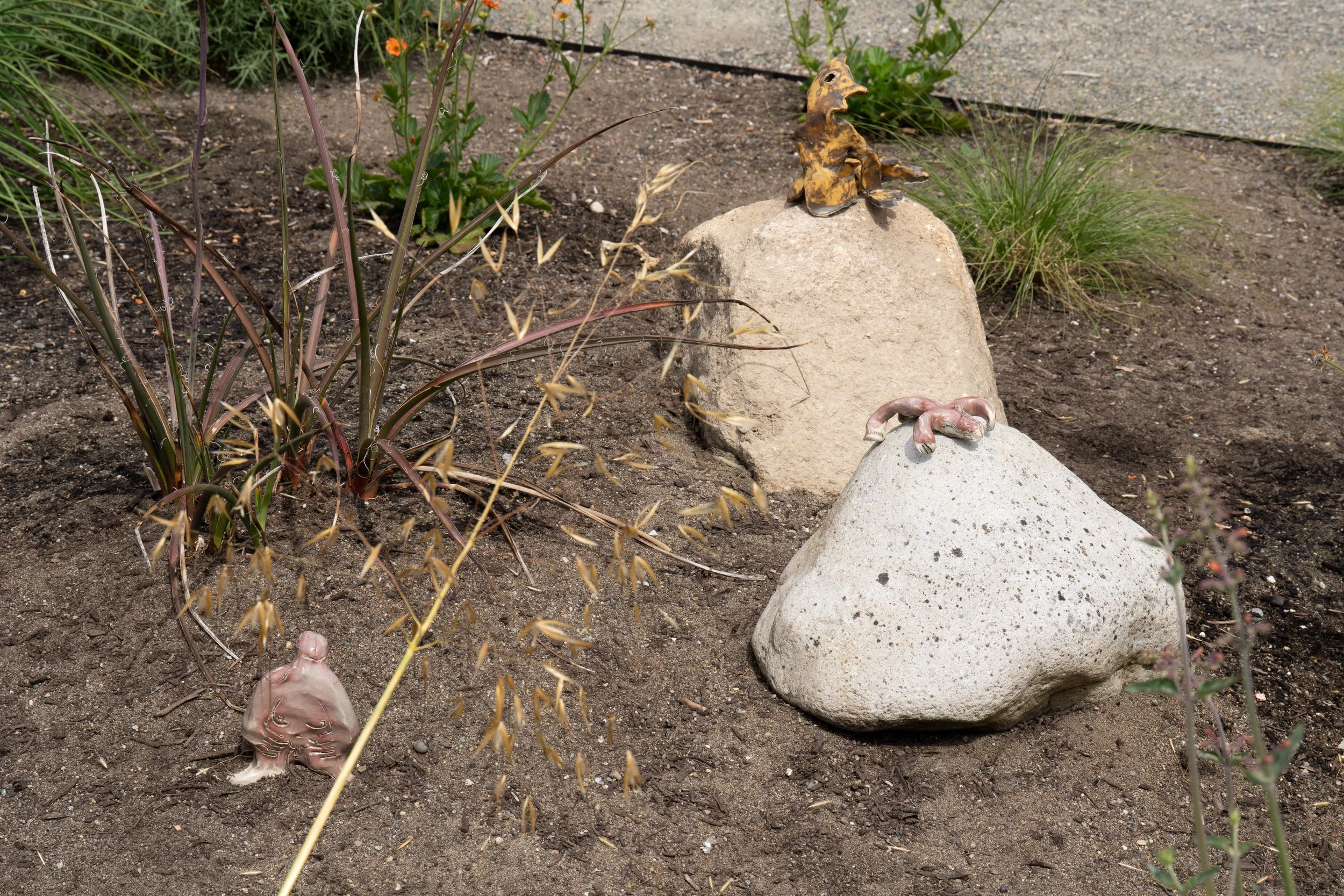 3 ceramic figures in a garden.
