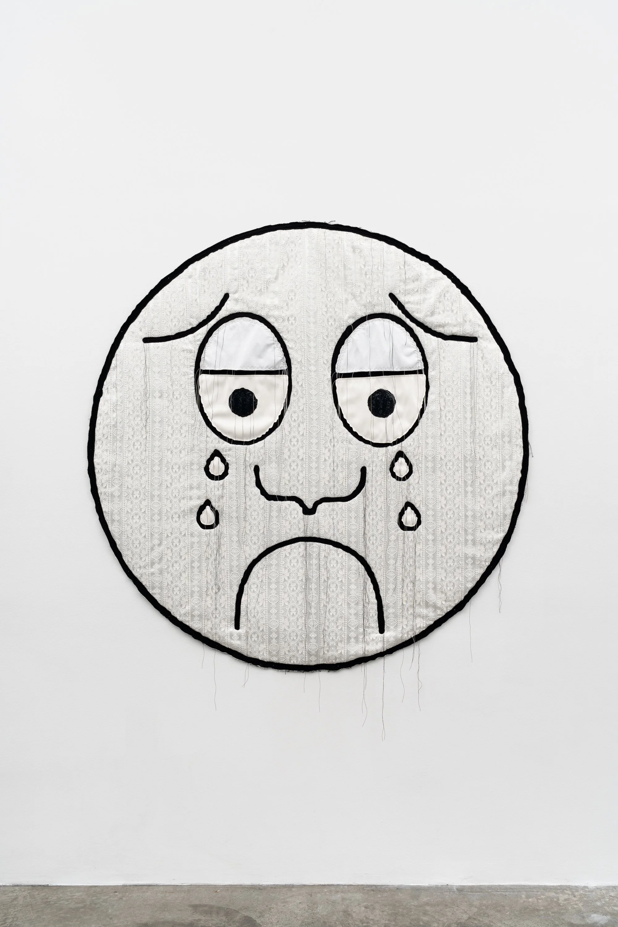 a cartoon crying face made with textile on the wall