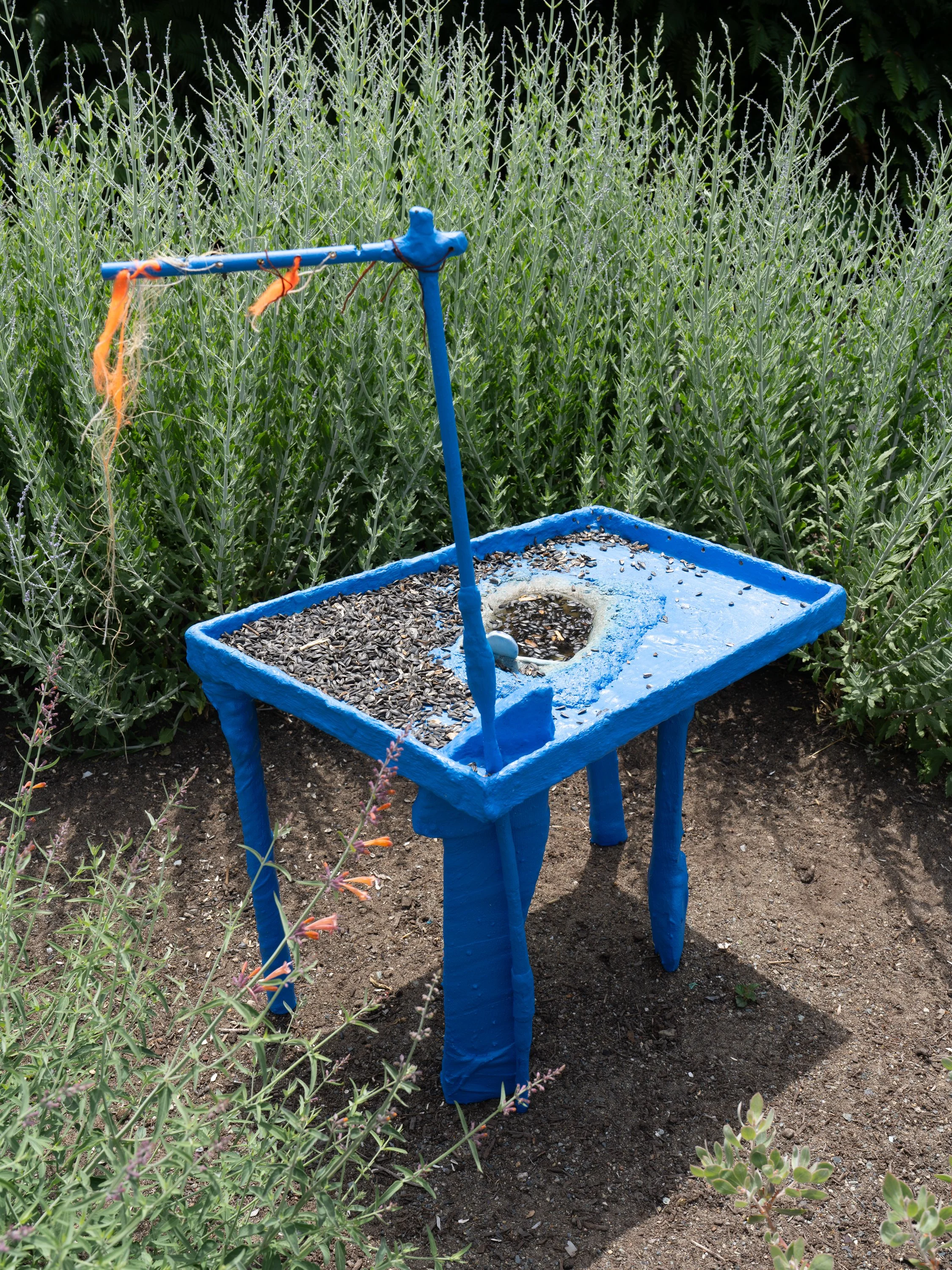 Blue sculpture with sunflower seeds in a garden.