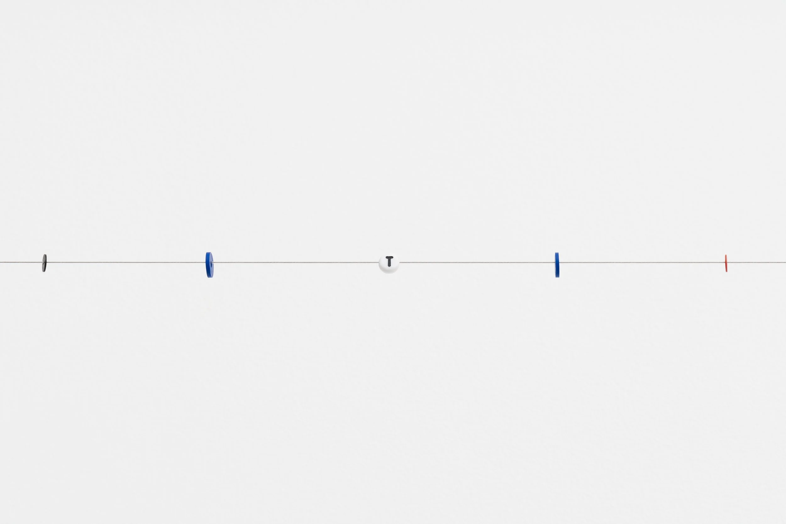 small beads on a wire; one of them reads letter T