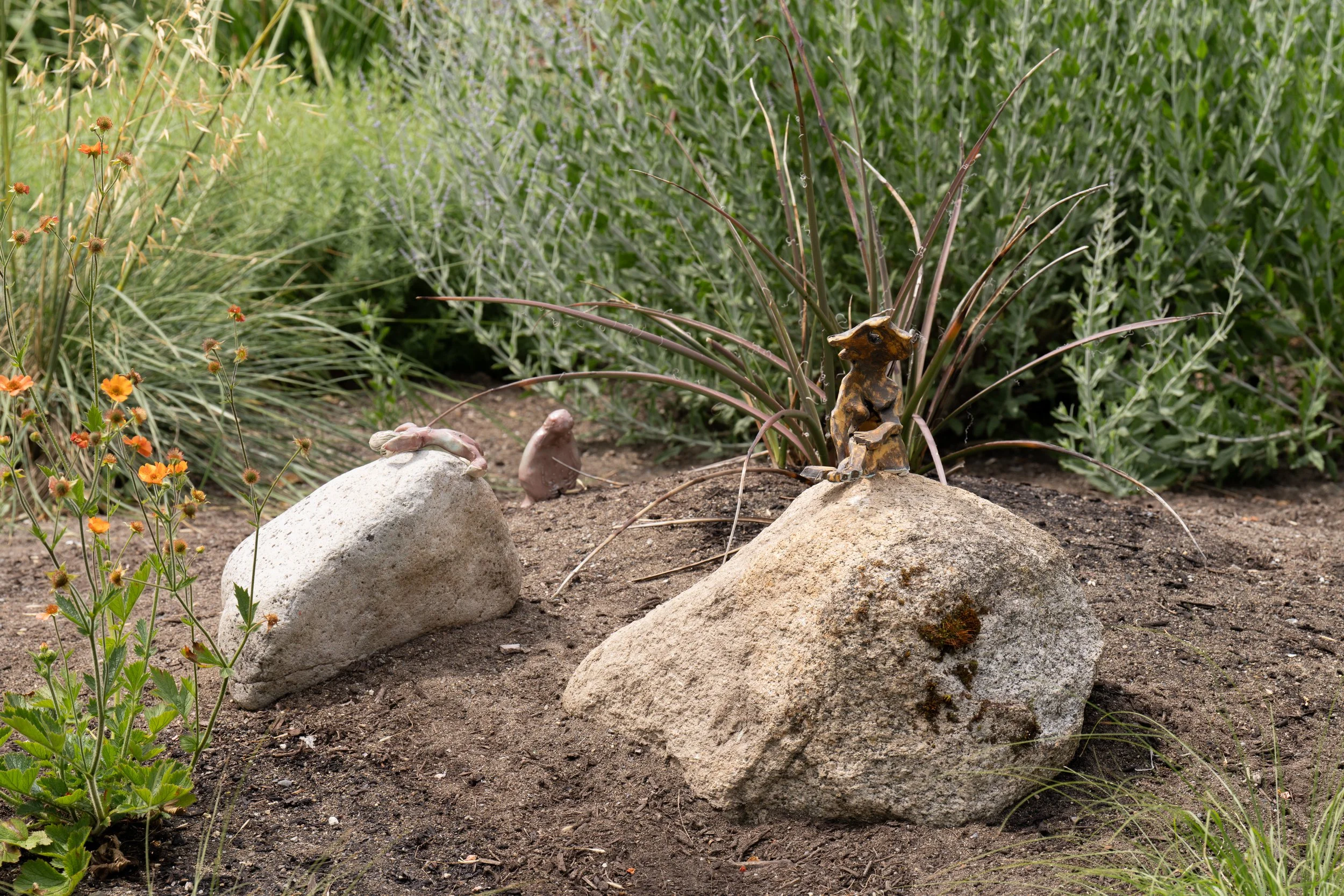 3 ceramic figures in a garden.