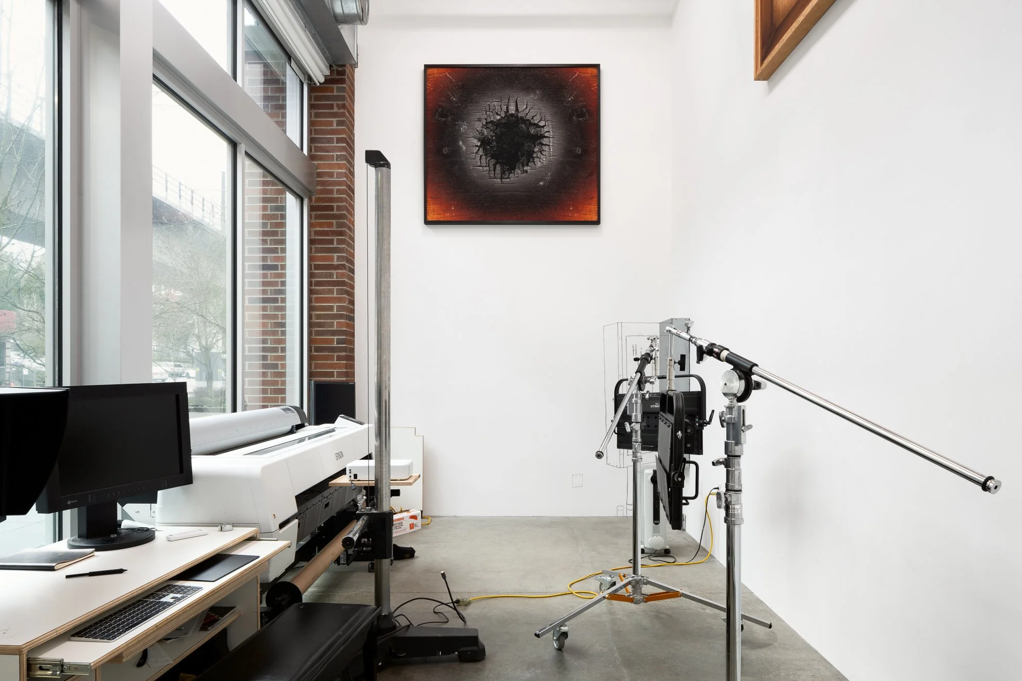View of a gallery space that includes artwork and the artist's production equipment.