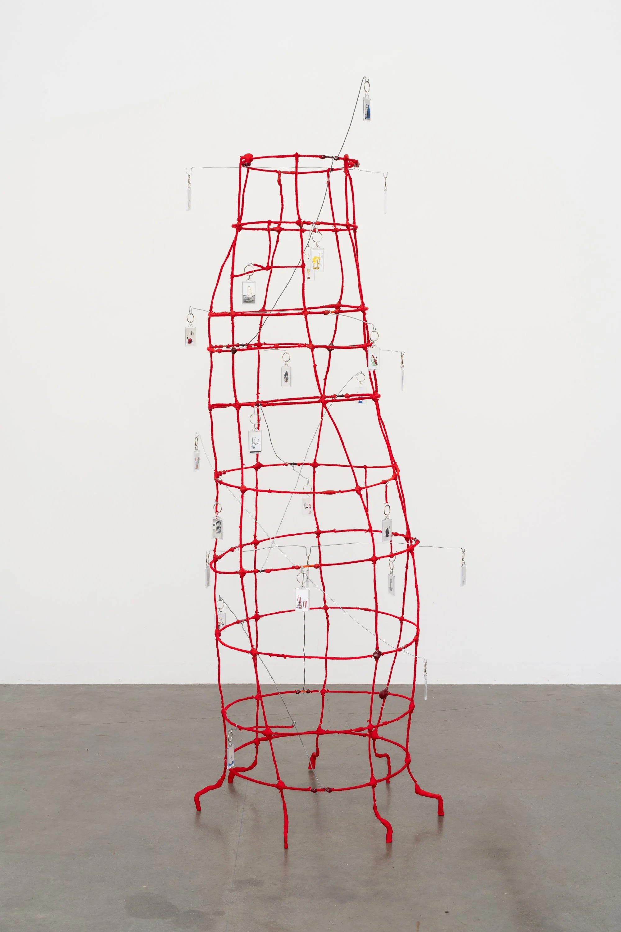 a wire tower wrapped in red yarn, with key chains hanging from bent wires