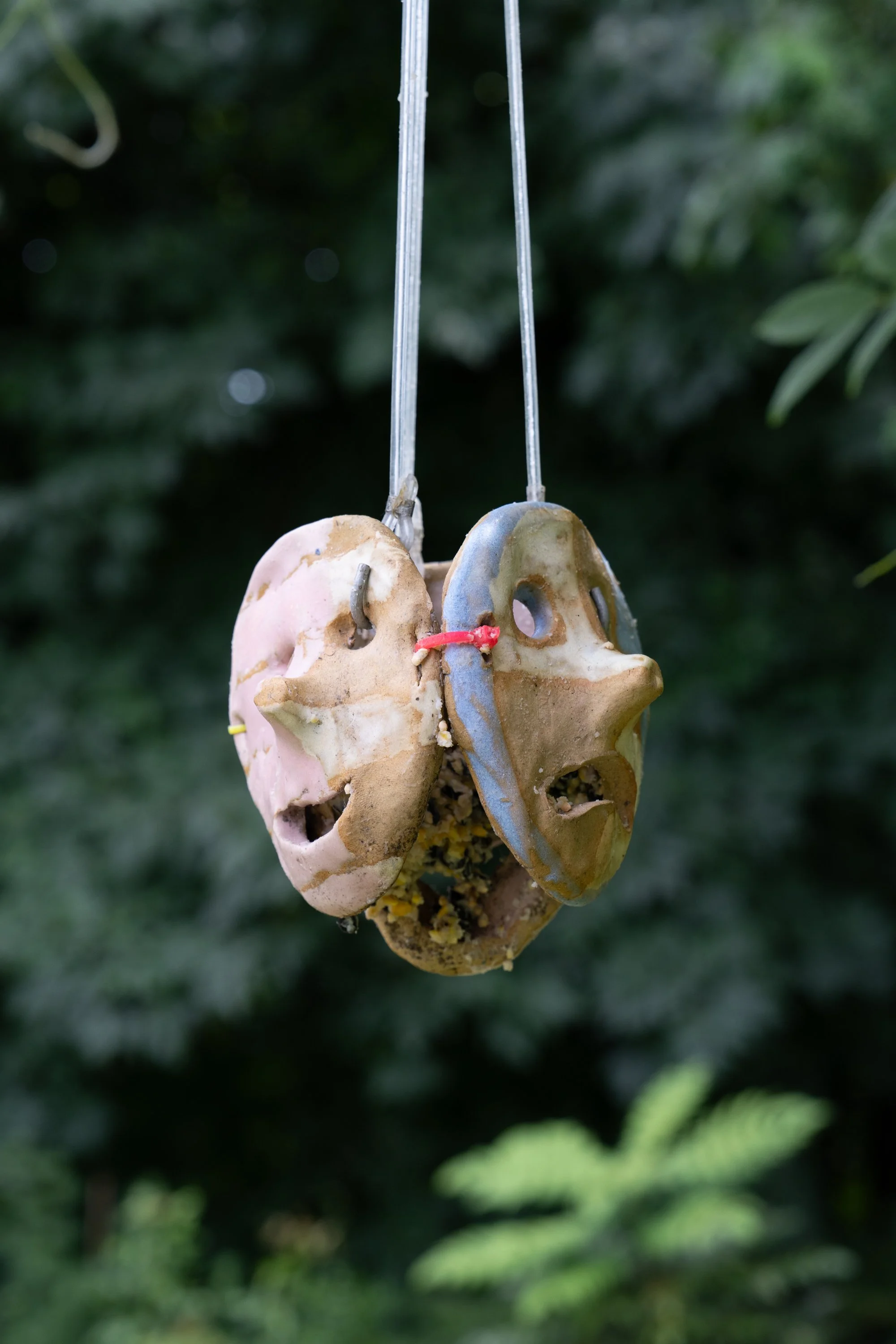 A ceramic sculpture with suet bird feed hanging from a tree.
