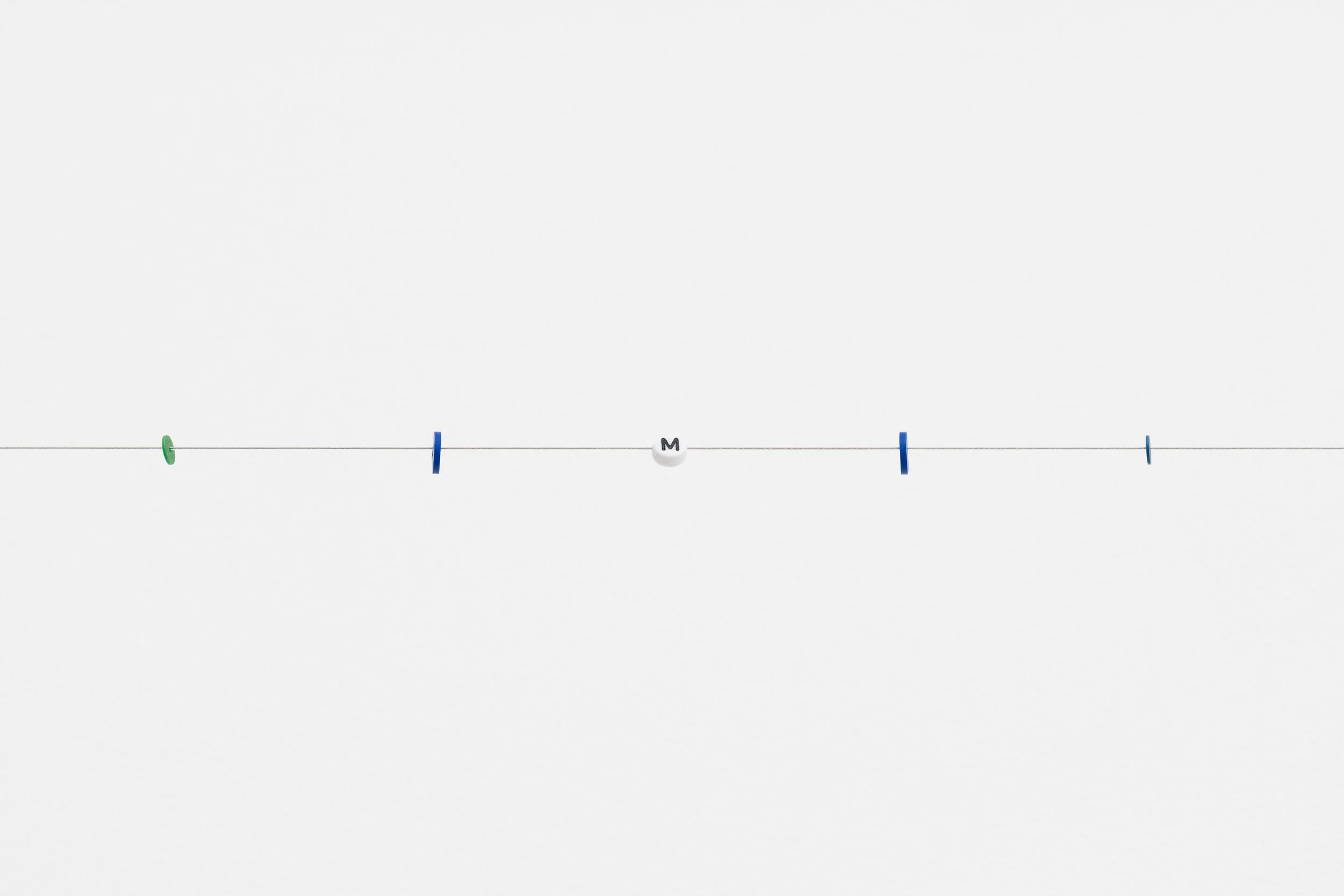small beads on a wire; one of them reads letter M