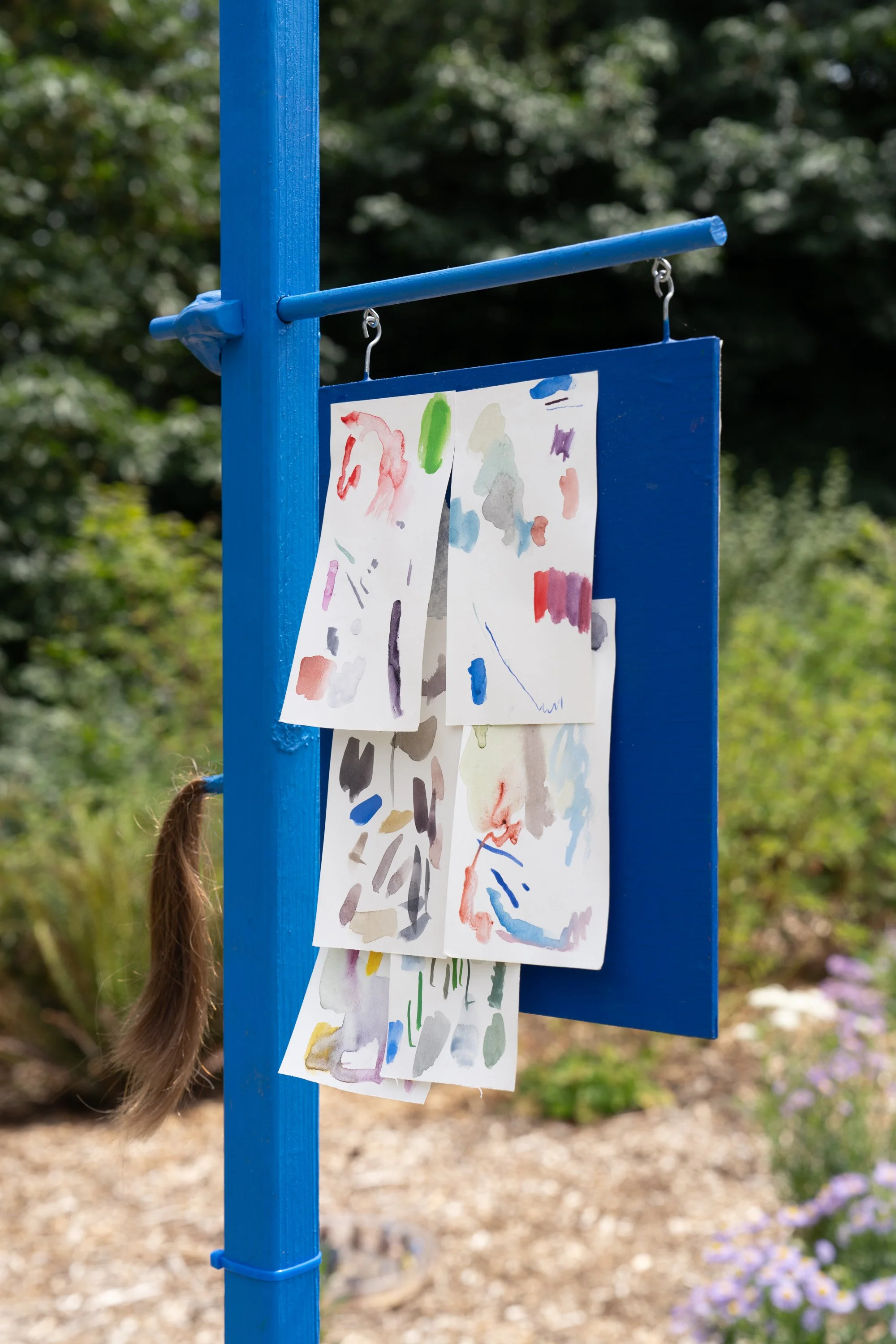Small watercolors hung on a blue sculpture.