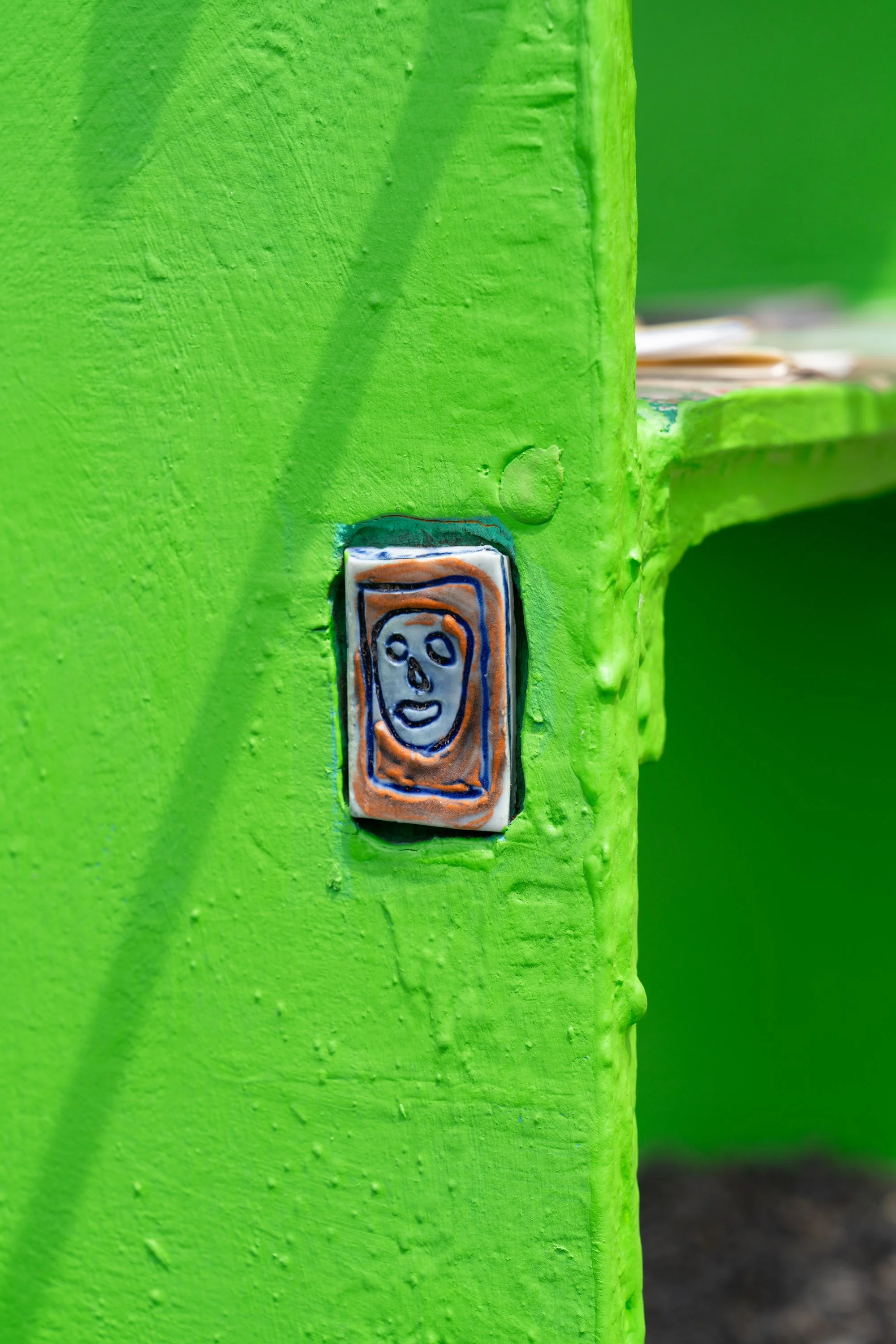A green sculpture with an embedded clay tile.