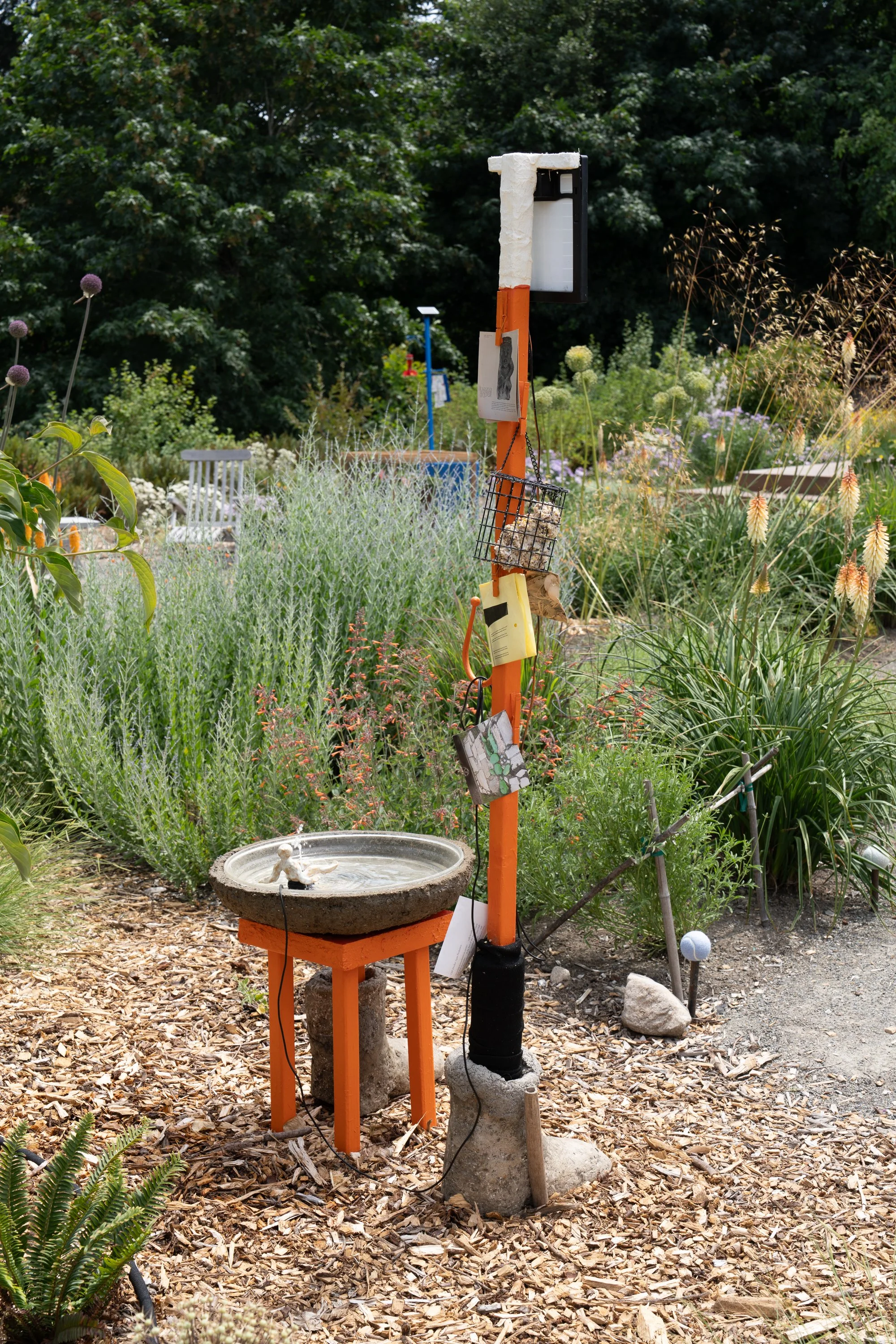 An orange sculpture in a garden.