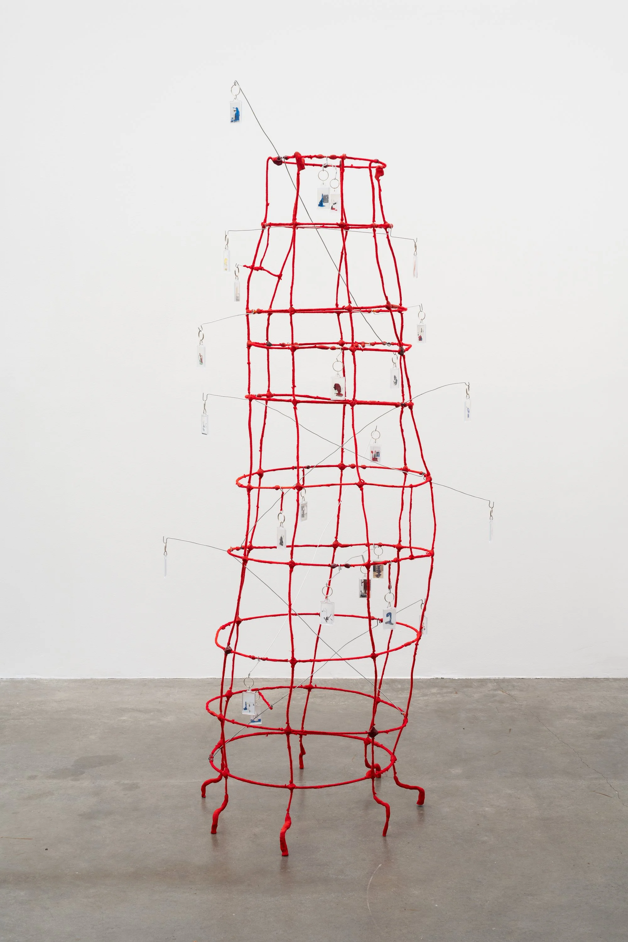 a wire tower wrapped in red yarn, with key chains hanging from bent wires