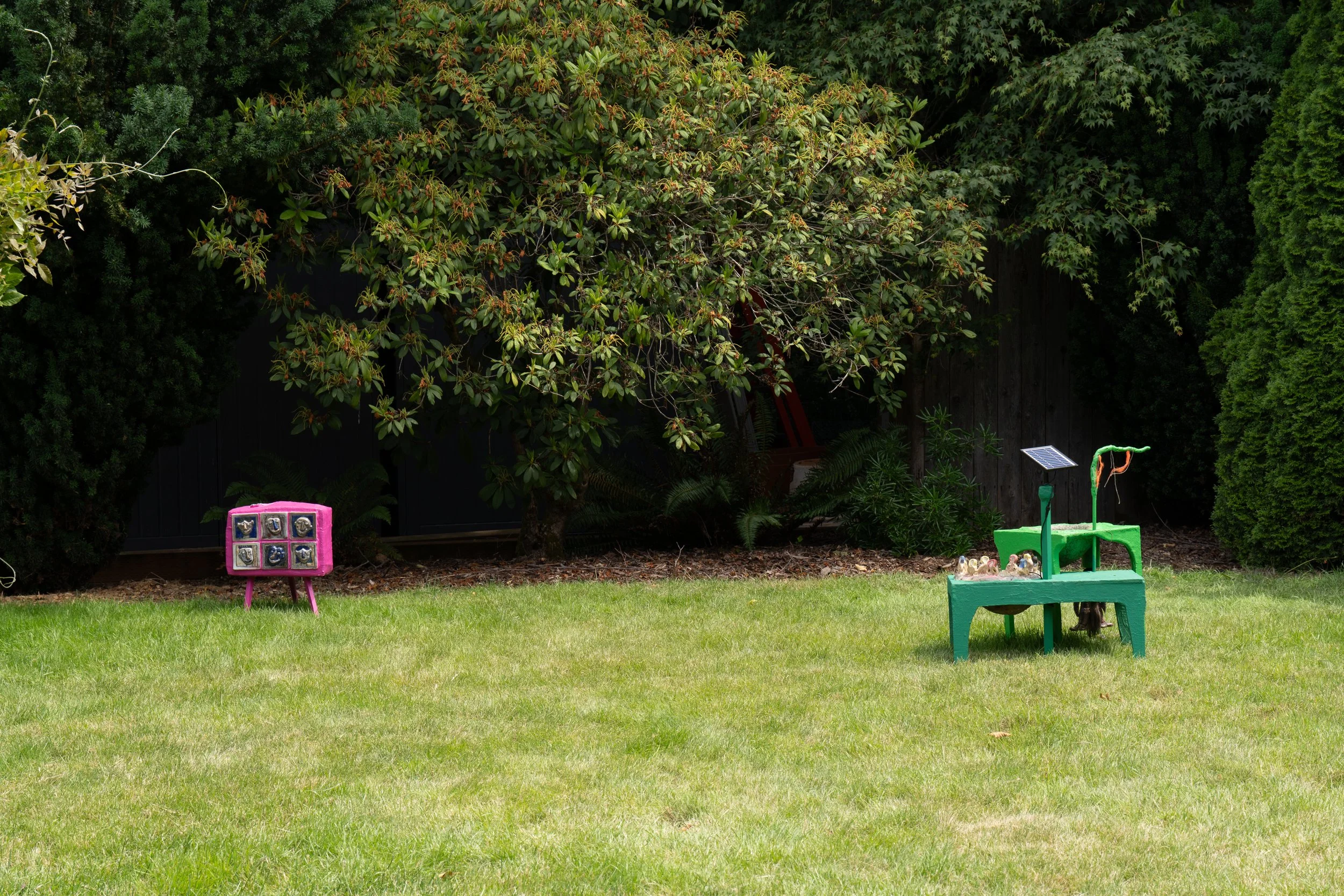 A pink sculpture and a green sculpture on a lawn.