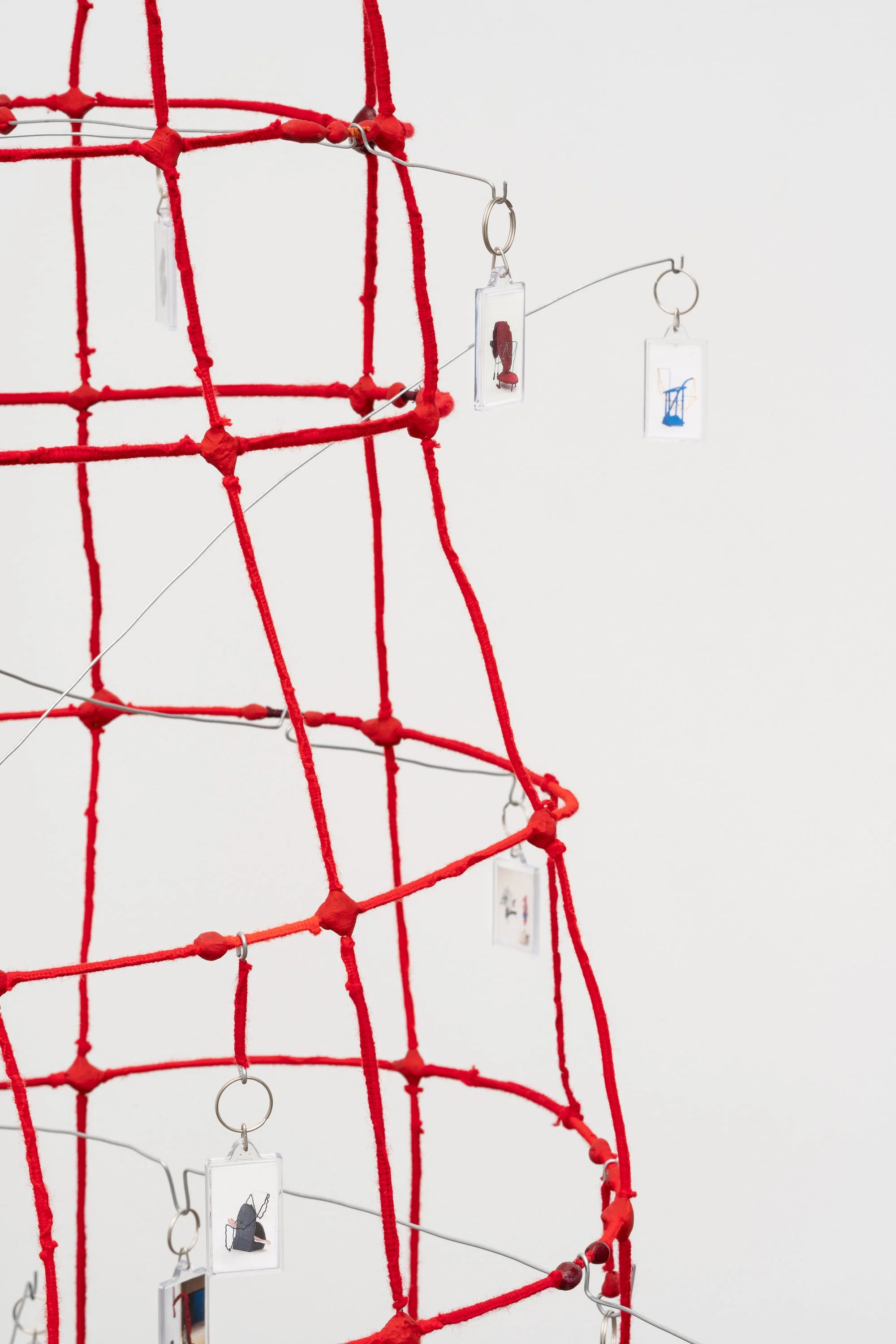 a wire tower wrapped in red yarn, with key chains hanging from bent wires