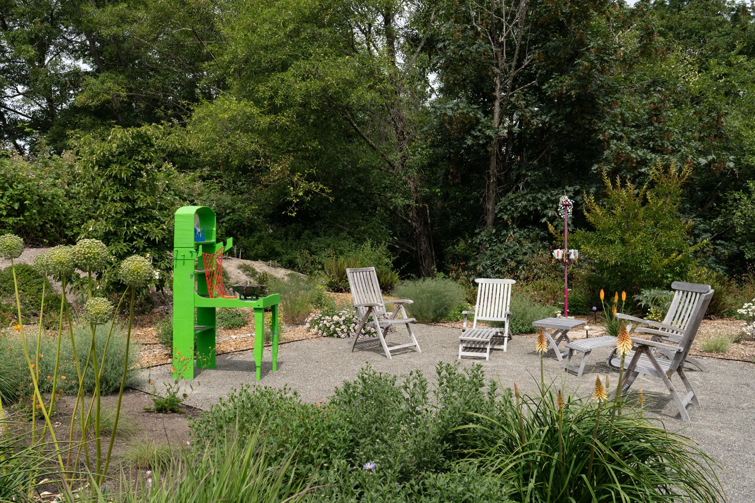 A green sculpture and a pink sculpture in a garden.