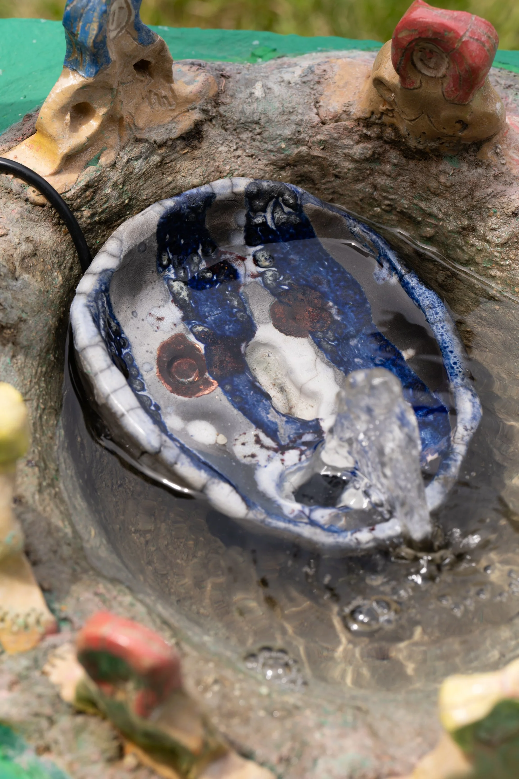 A water fountain with a ceramic tray and ceramic figures.
