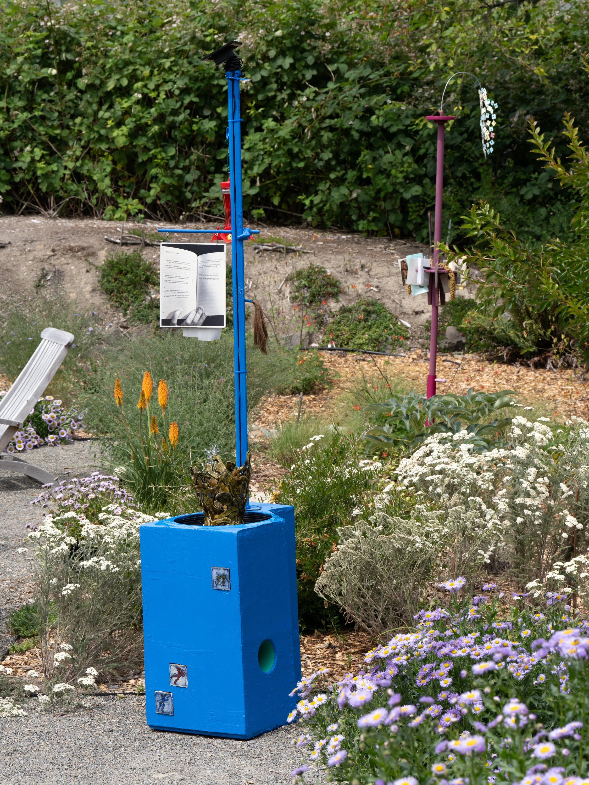 A blue sculpture and a pink sculpture in a garden.