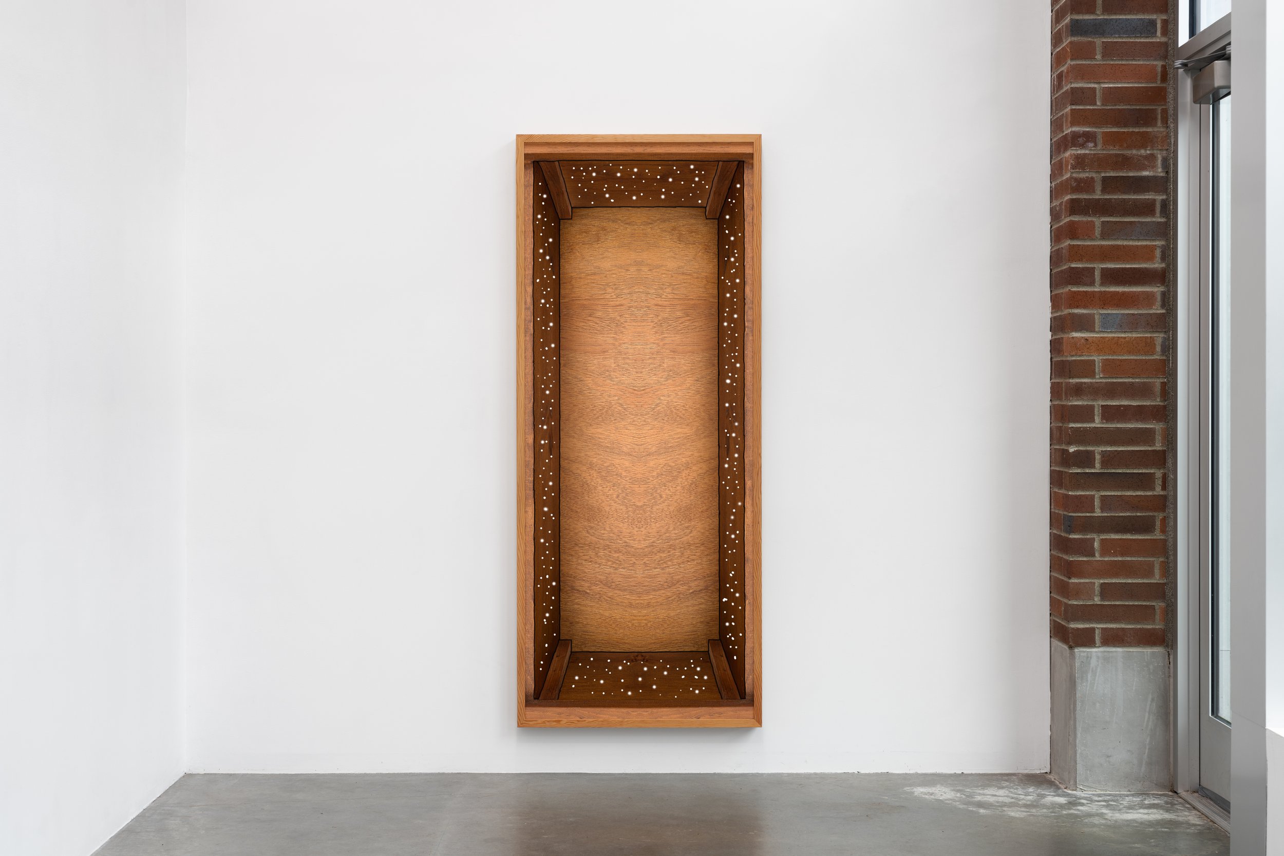 A small art gallery showing a large photograph depicting the interior of a vertical rectangular wooden box.