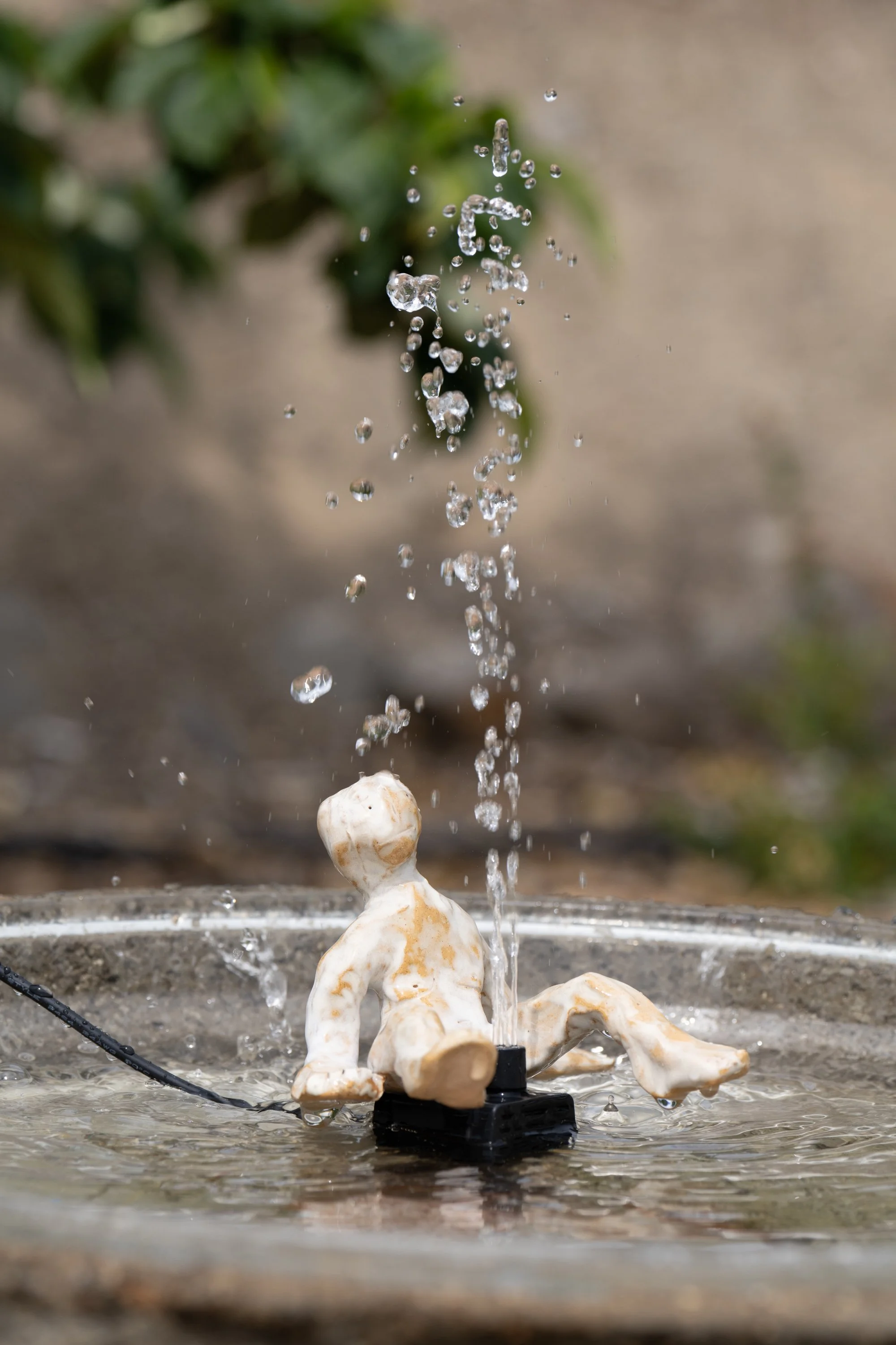 A water fountain that looks like a ceramic figure is peeing.