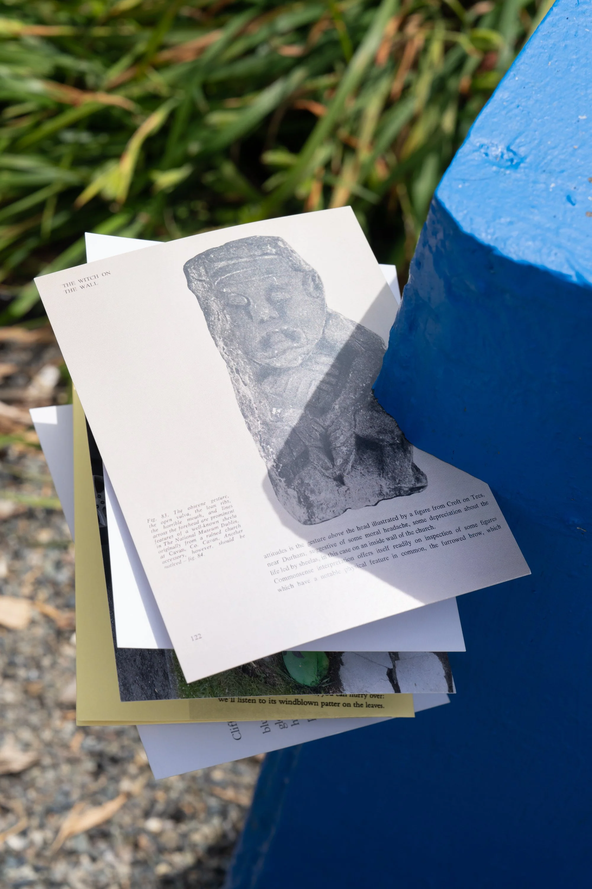 Various postcards and papers held by a blue sculpture.