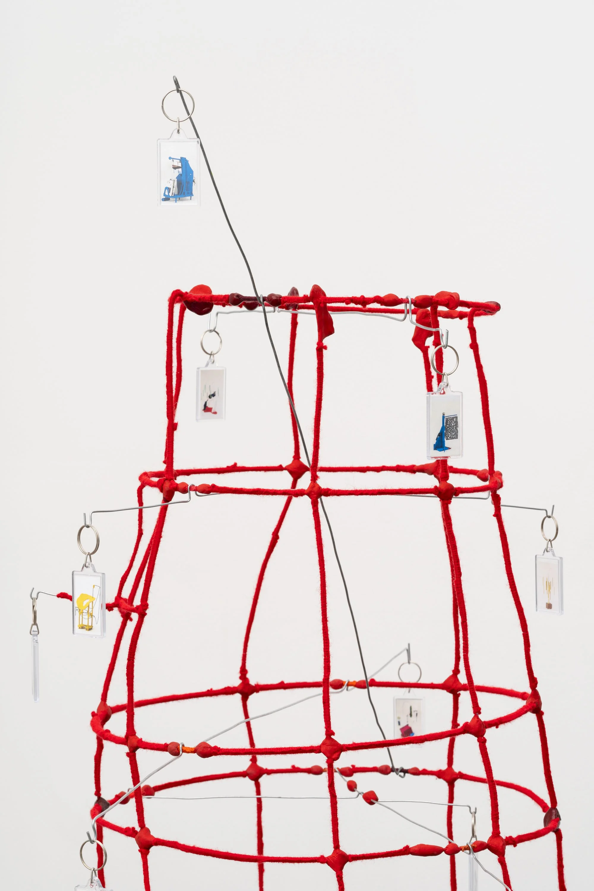 a wire tower wrapped in red yarn, with key chains hanging from bent wires