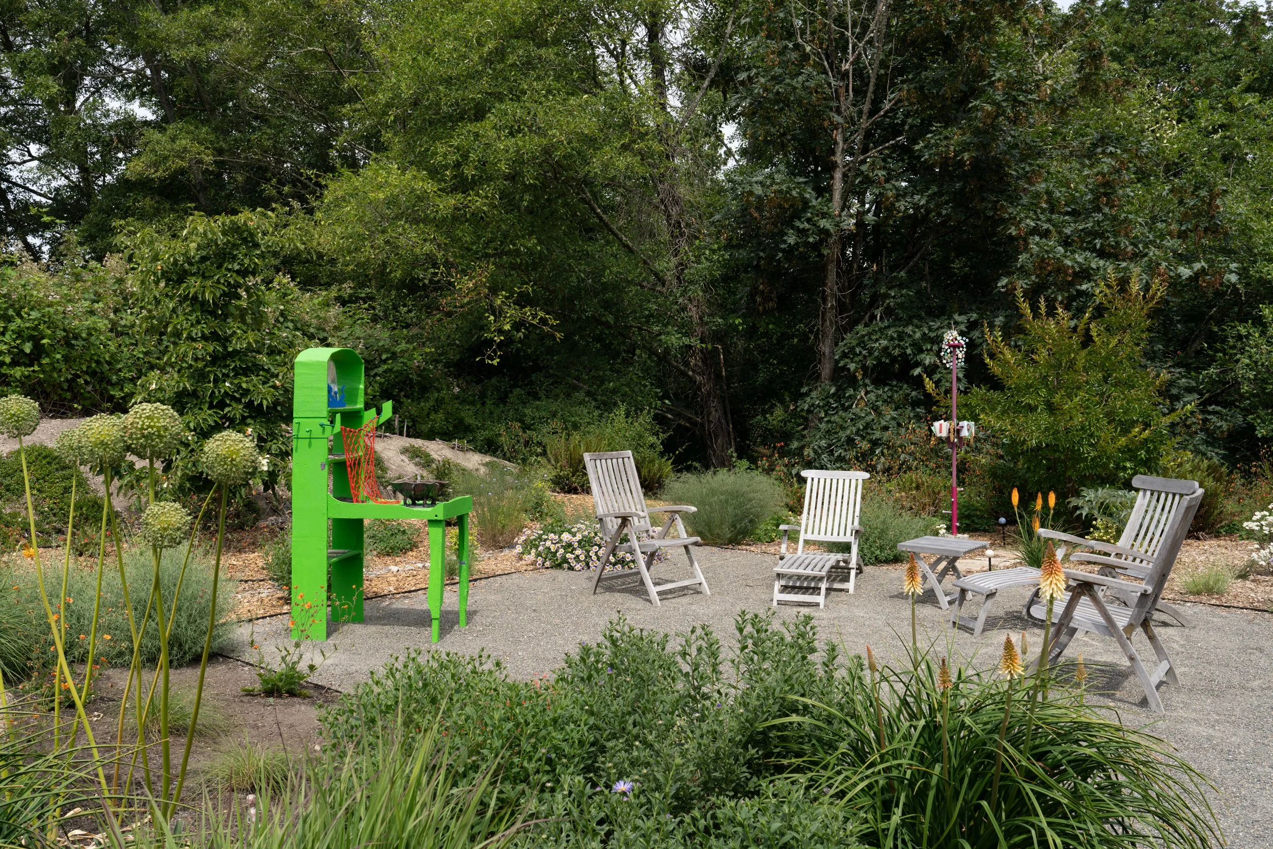 A green sculpture and a pink sculpture in a garden.