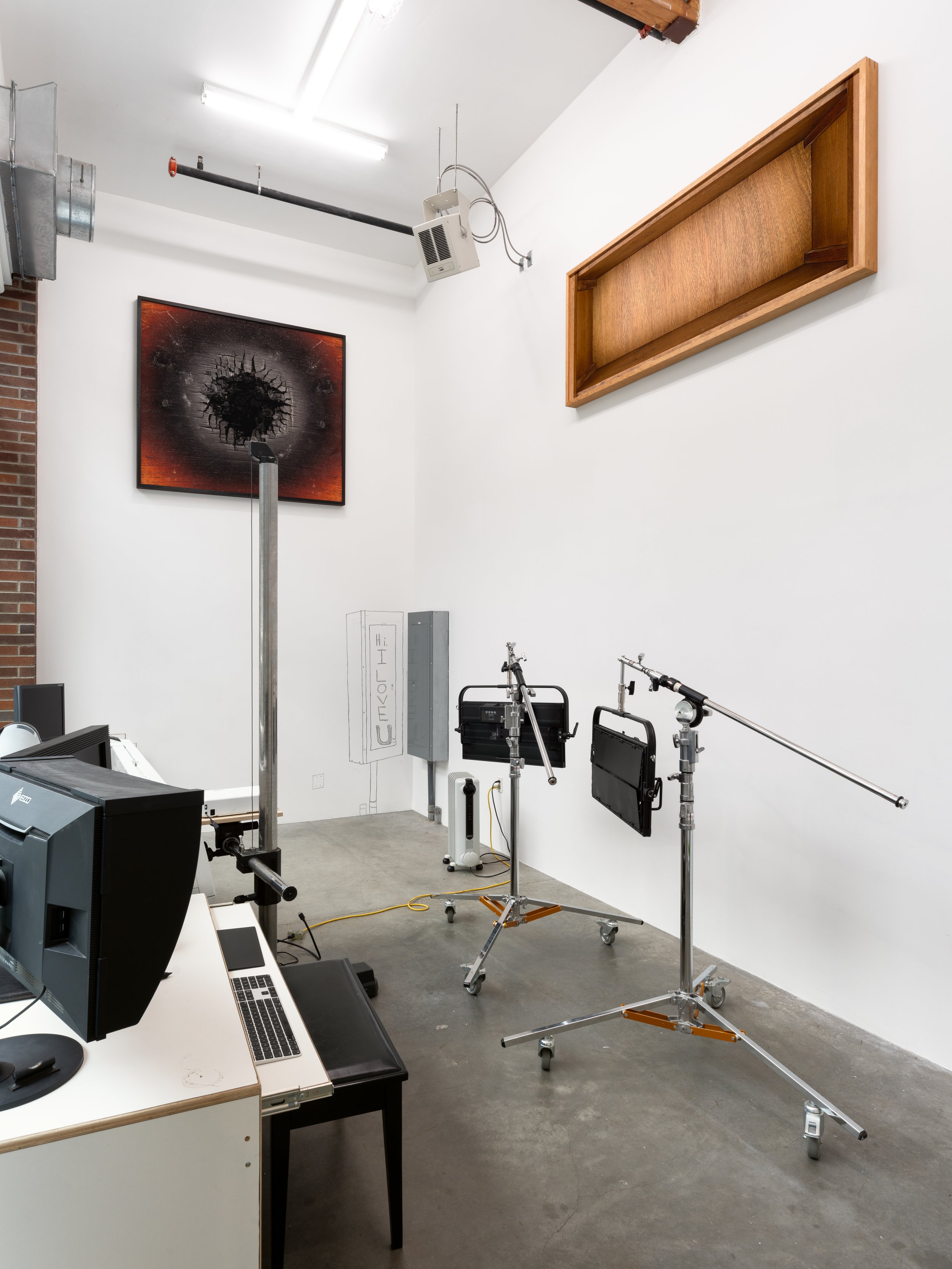 Gallery space with digital photo equip and photographs hung very high on the walls. There is also a drtawing of a panel box next to the room's panel box.