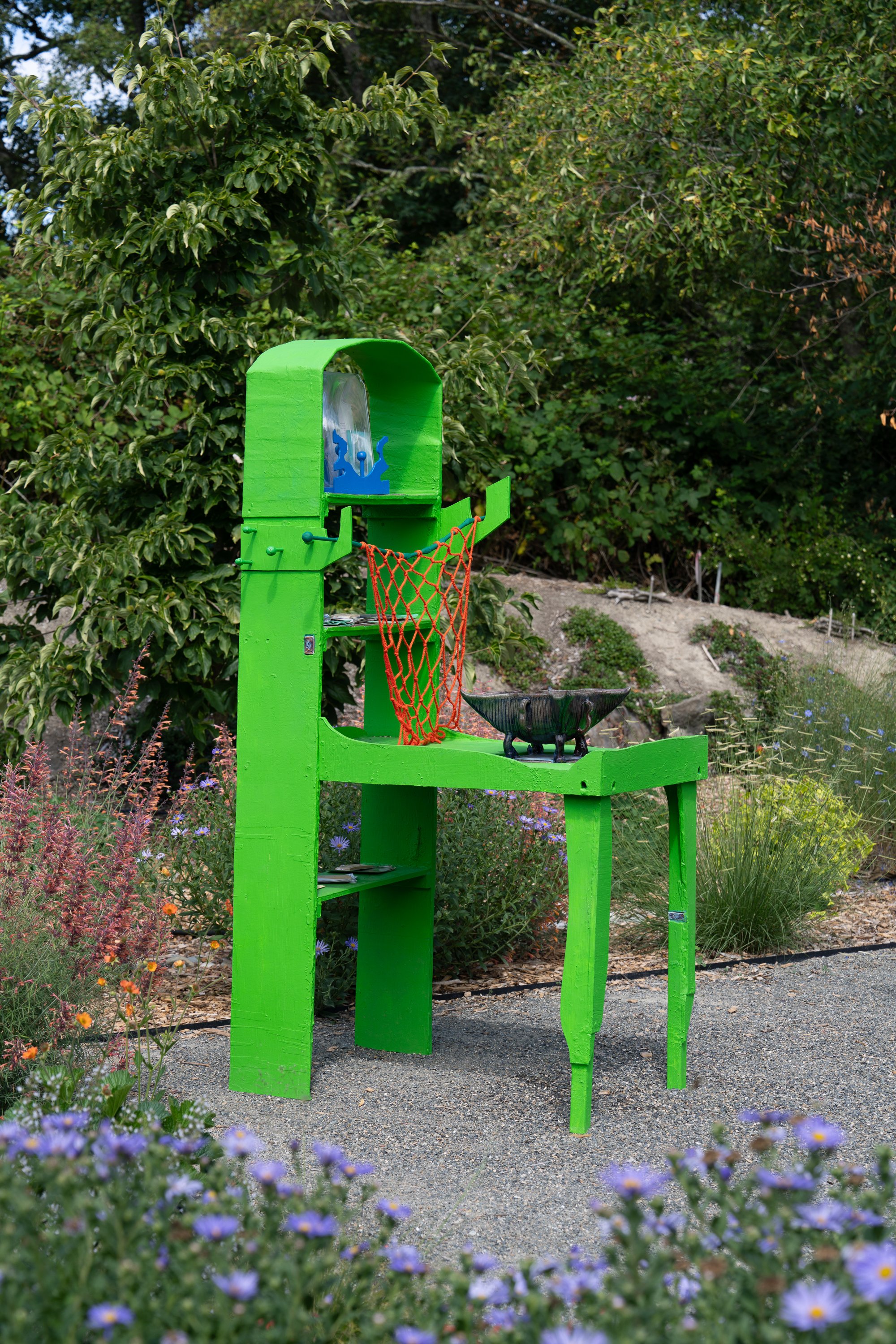 Bright green sculpture with a fountain in a garden.